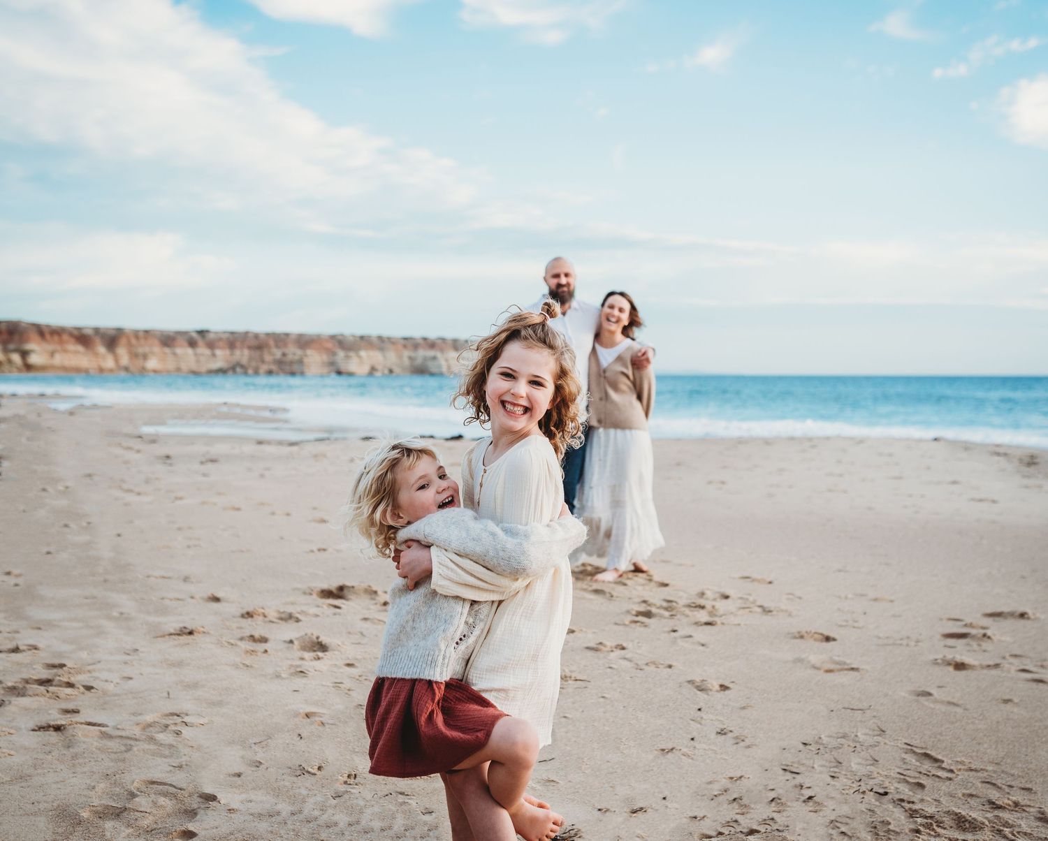 Joyful beach photoshoot with sandy coastline and ocean waves in the background.