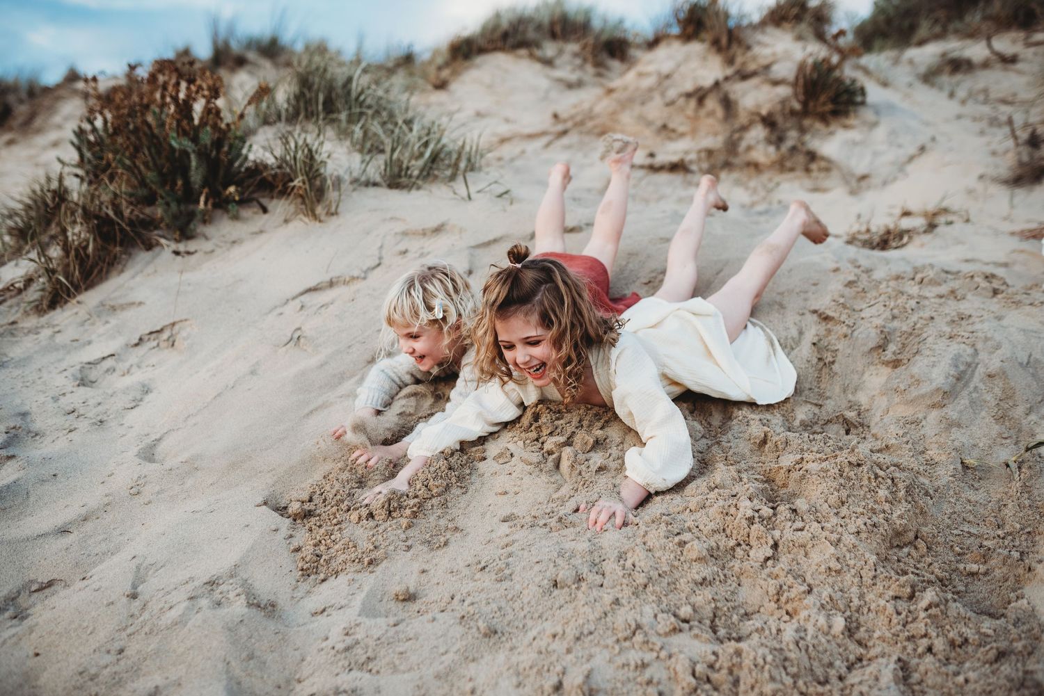 Playful interactions on sandy dunes with beach grass during sunset.