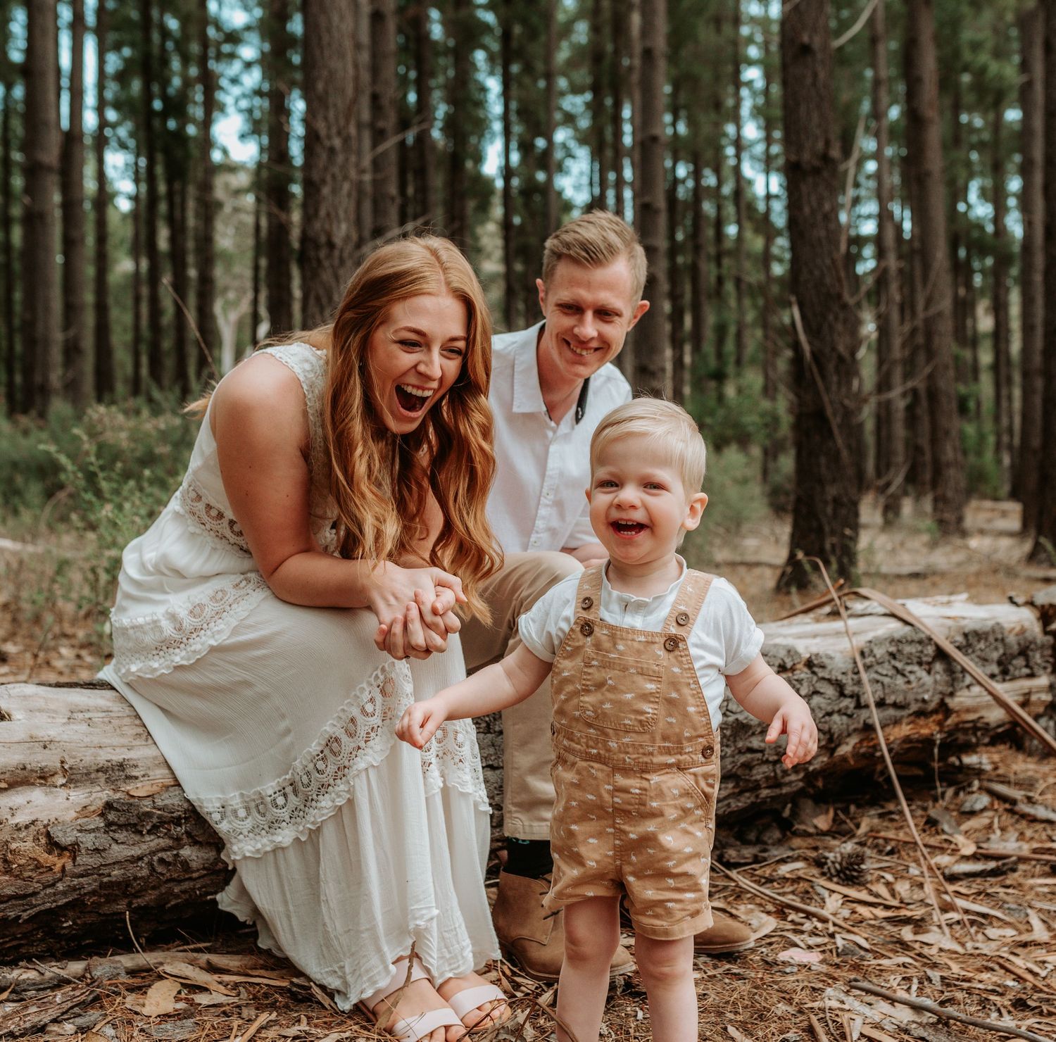 A family shares a joyful moment together in a pine forest setting.