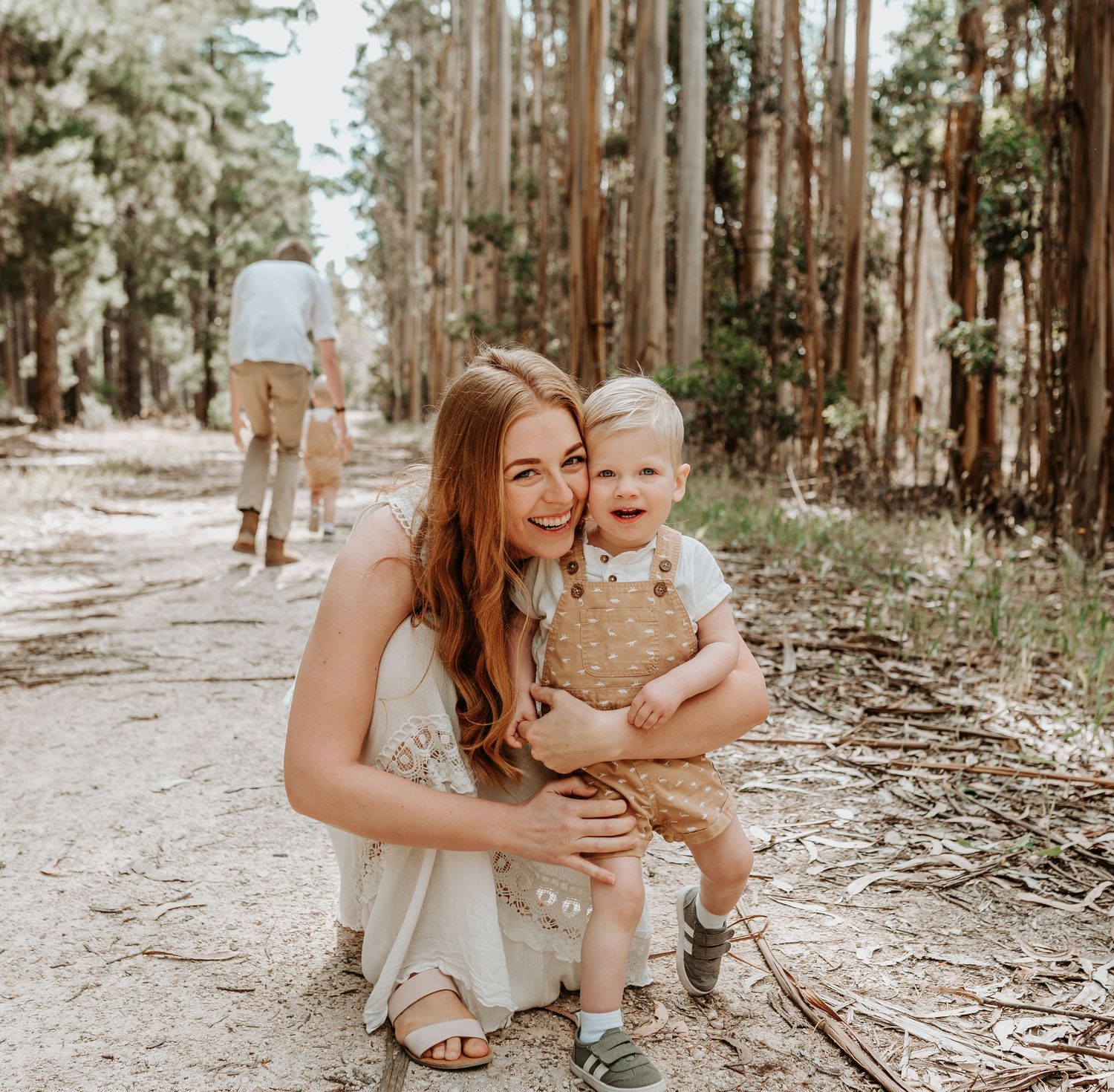 Mother and baby share joyful moments together while playing in a eucalyptus forest on a sunny afternoon.