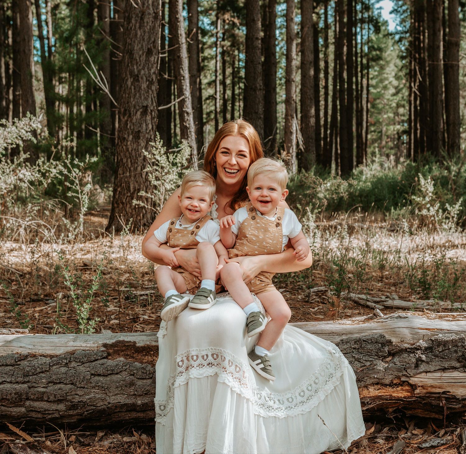 A joyful family moment captured in a serene forest setting with everyone wearing coordinating white outfits.
