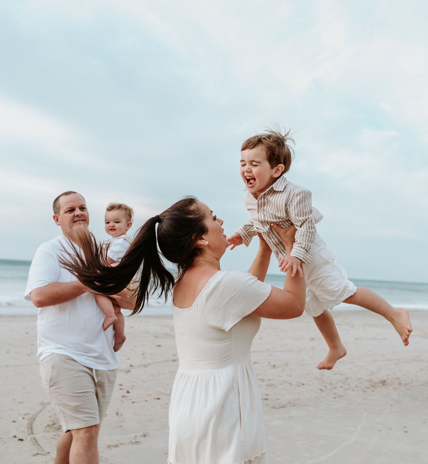 Playful family moments captured on a beach as parents lift and swing their child in the air.