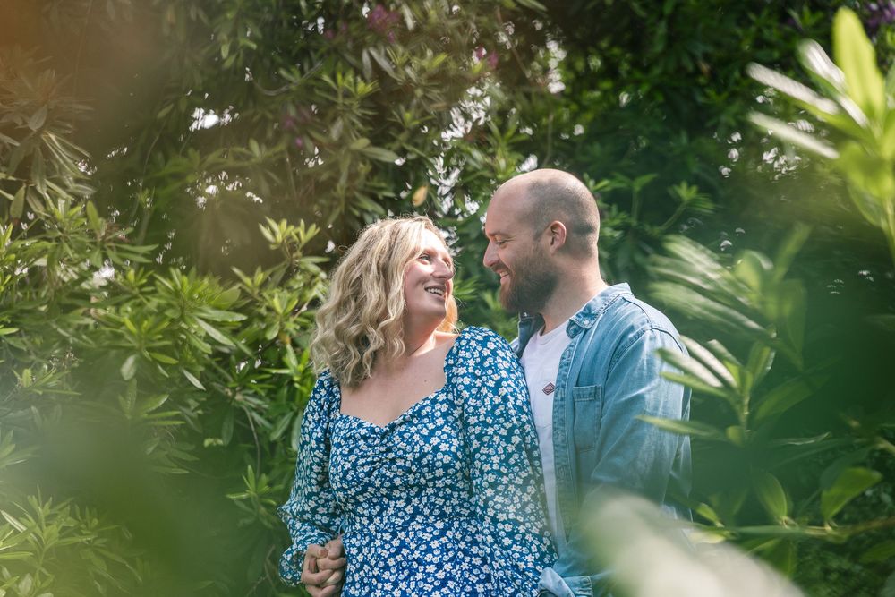 A couple shares an intimate moment in a lush garden setting with soft natural lighting.