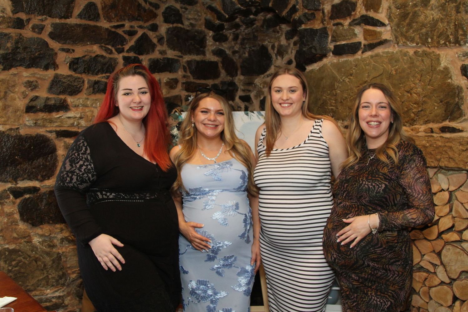 Group photo at a baby shower celebration with stone wall backdrop.