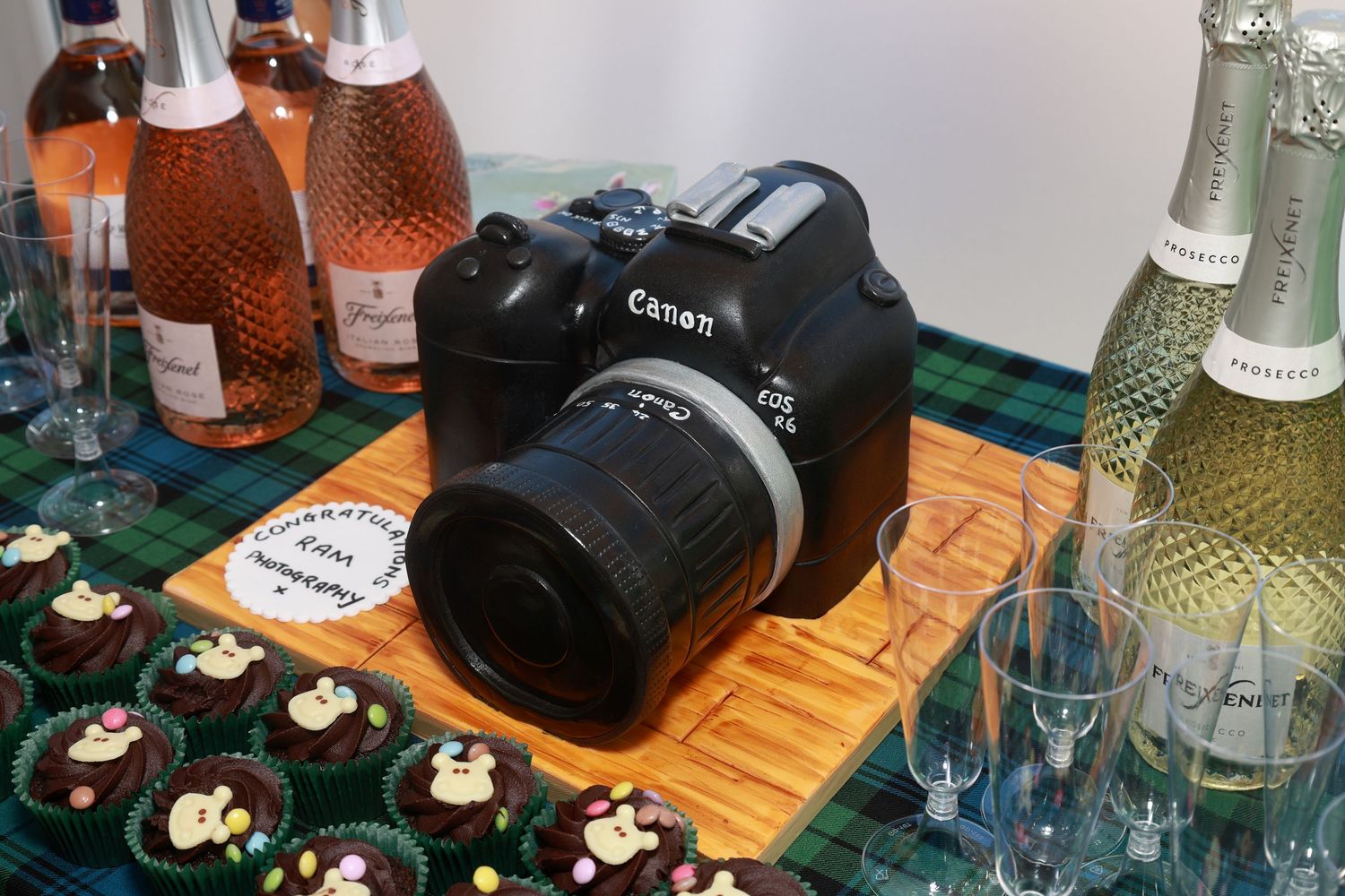 Bottles and camera equipment arranged on a wooden surface at a party or event setting.