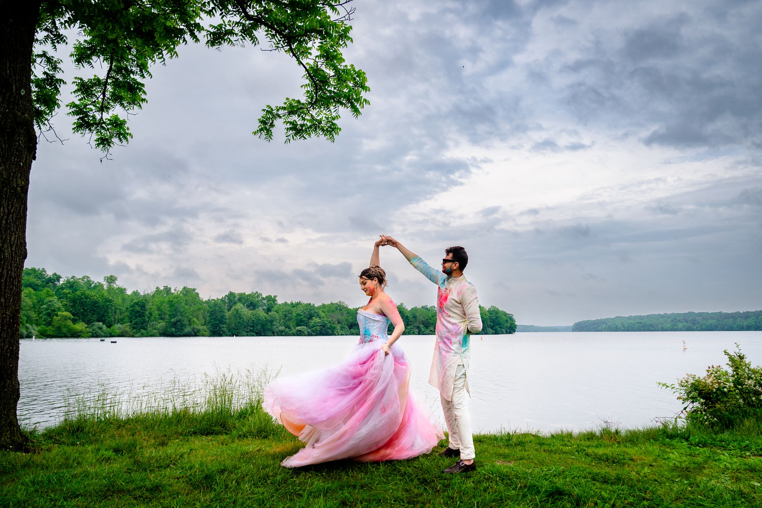 Scenic lakeside wedding portraits with cloudy skies and lush greenery in the background.