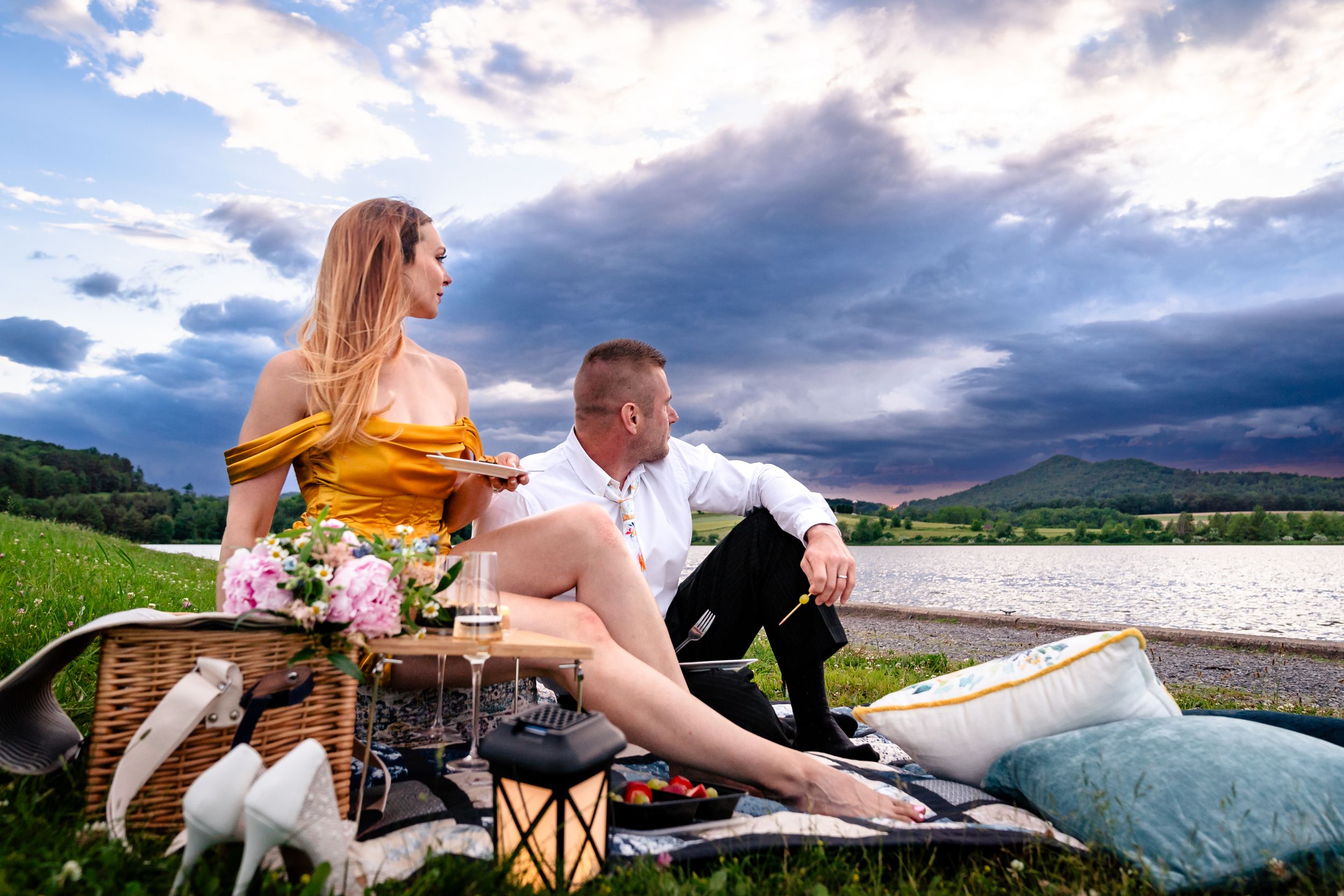 Romantic lakeside photo session with dramatic clouds and mountains in the background.