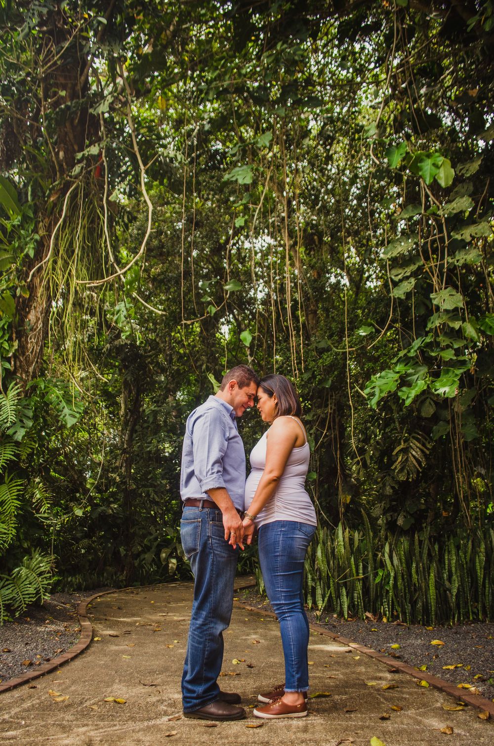 Couple holding hands and sharing a romantic moment in a lush tropical forest setting.
