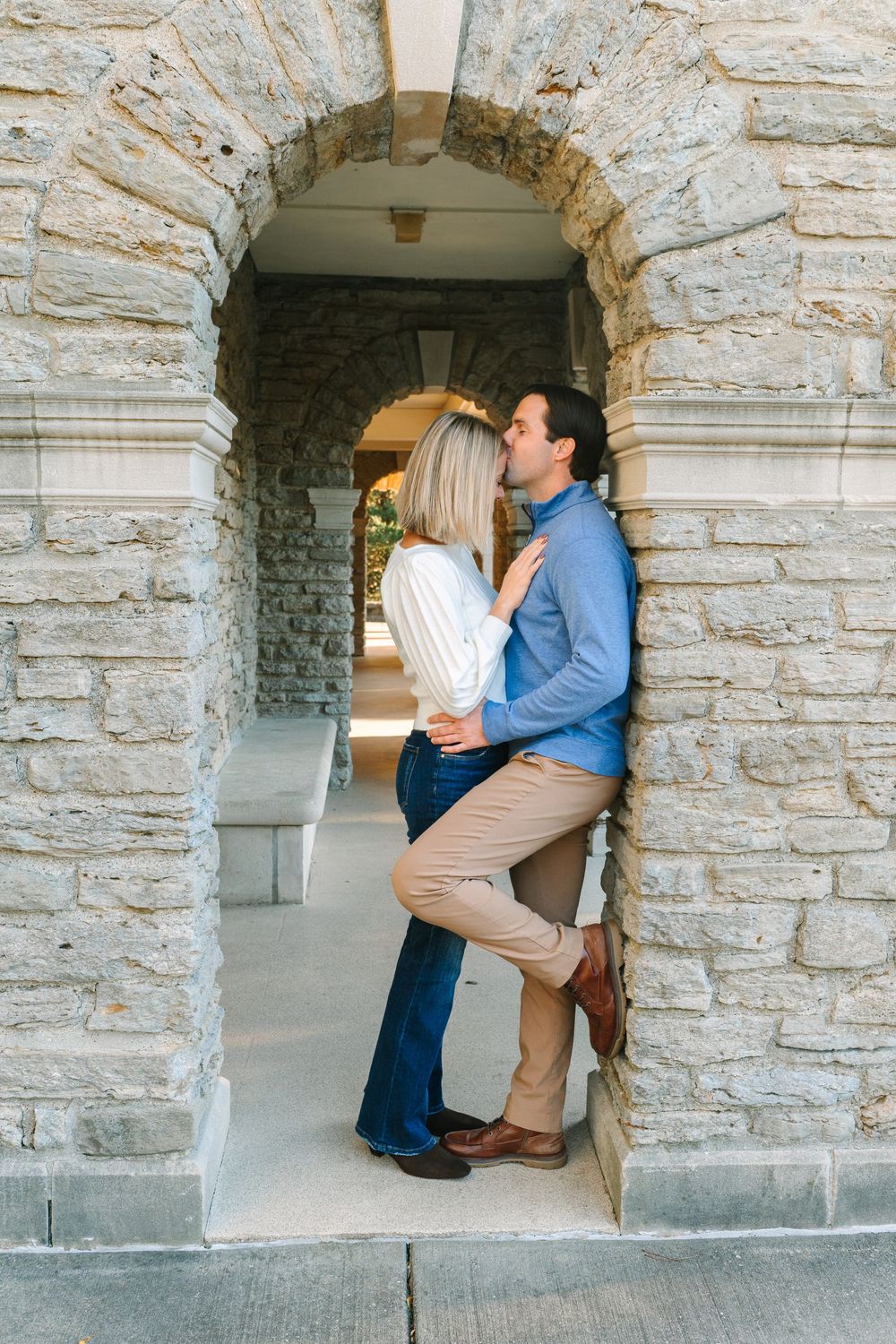 Romantic couple embracing in a stone archway during an engagement photoshoot.