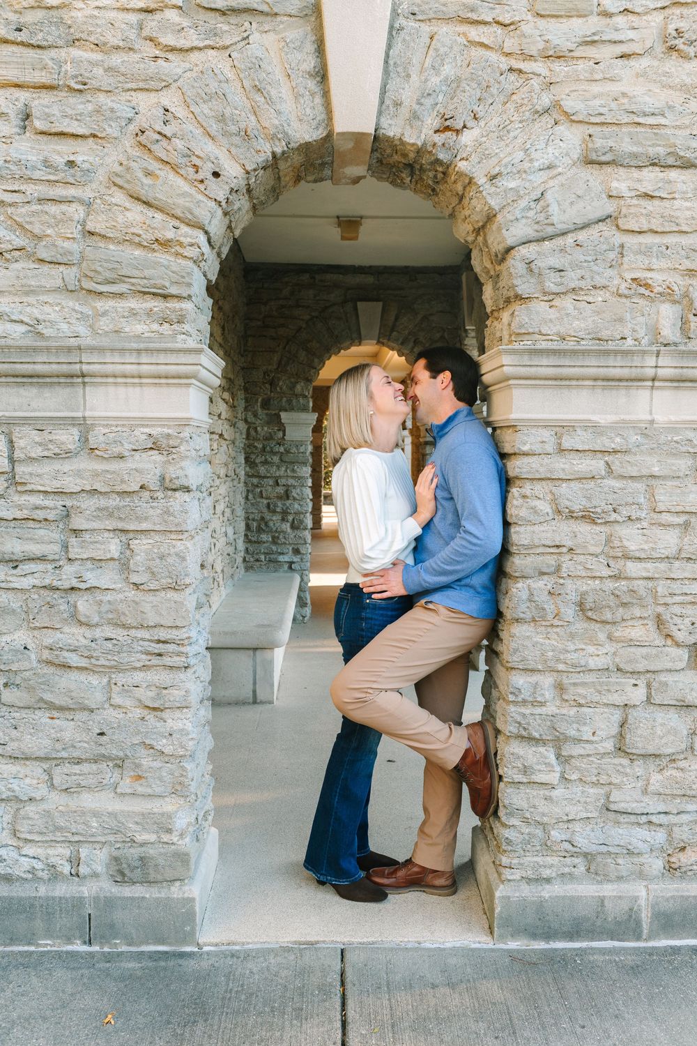 A romantic couple embraces in a stone archway during an engagement photoshoot.