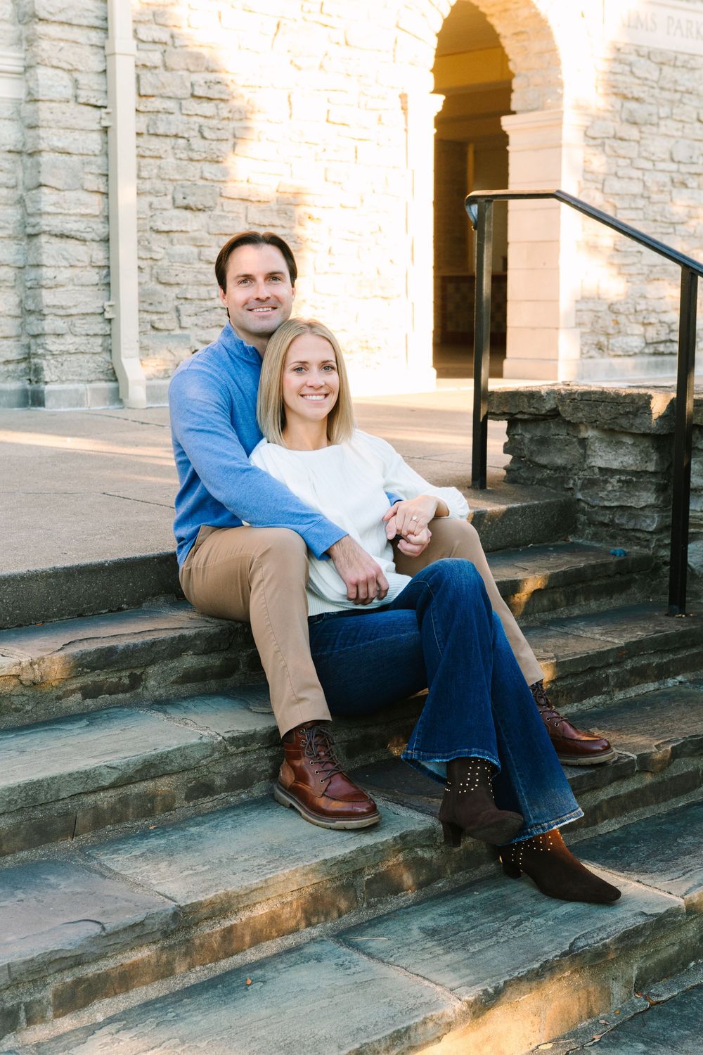 Couple sitting together on stone steps of a historic building during autumn.