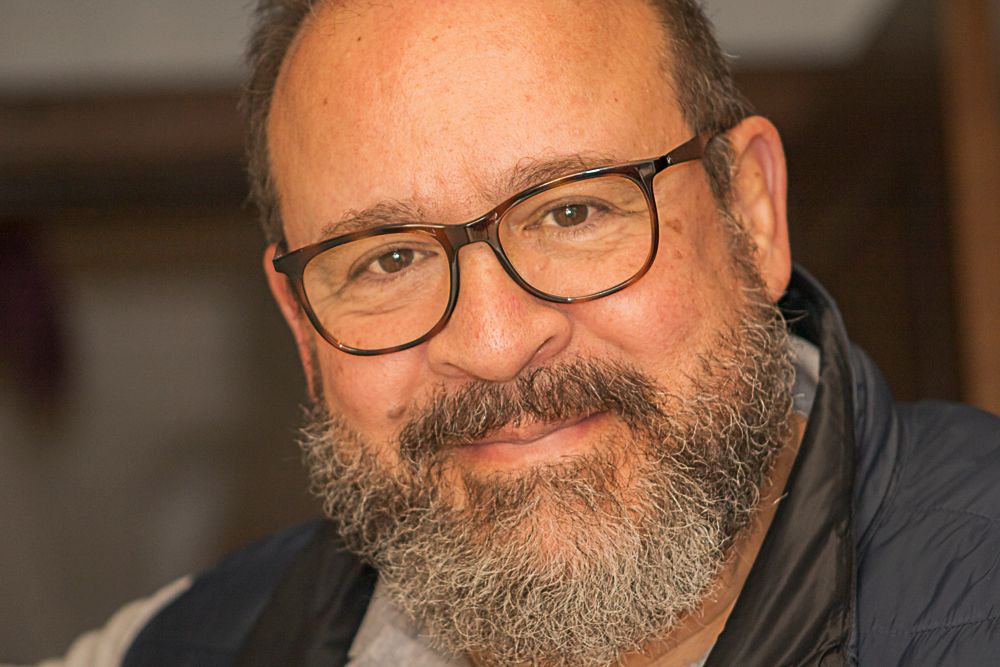 Professional portrait of bearded man with glasses in warm indoor lighting, photographed by Piret Victoria Ribas.