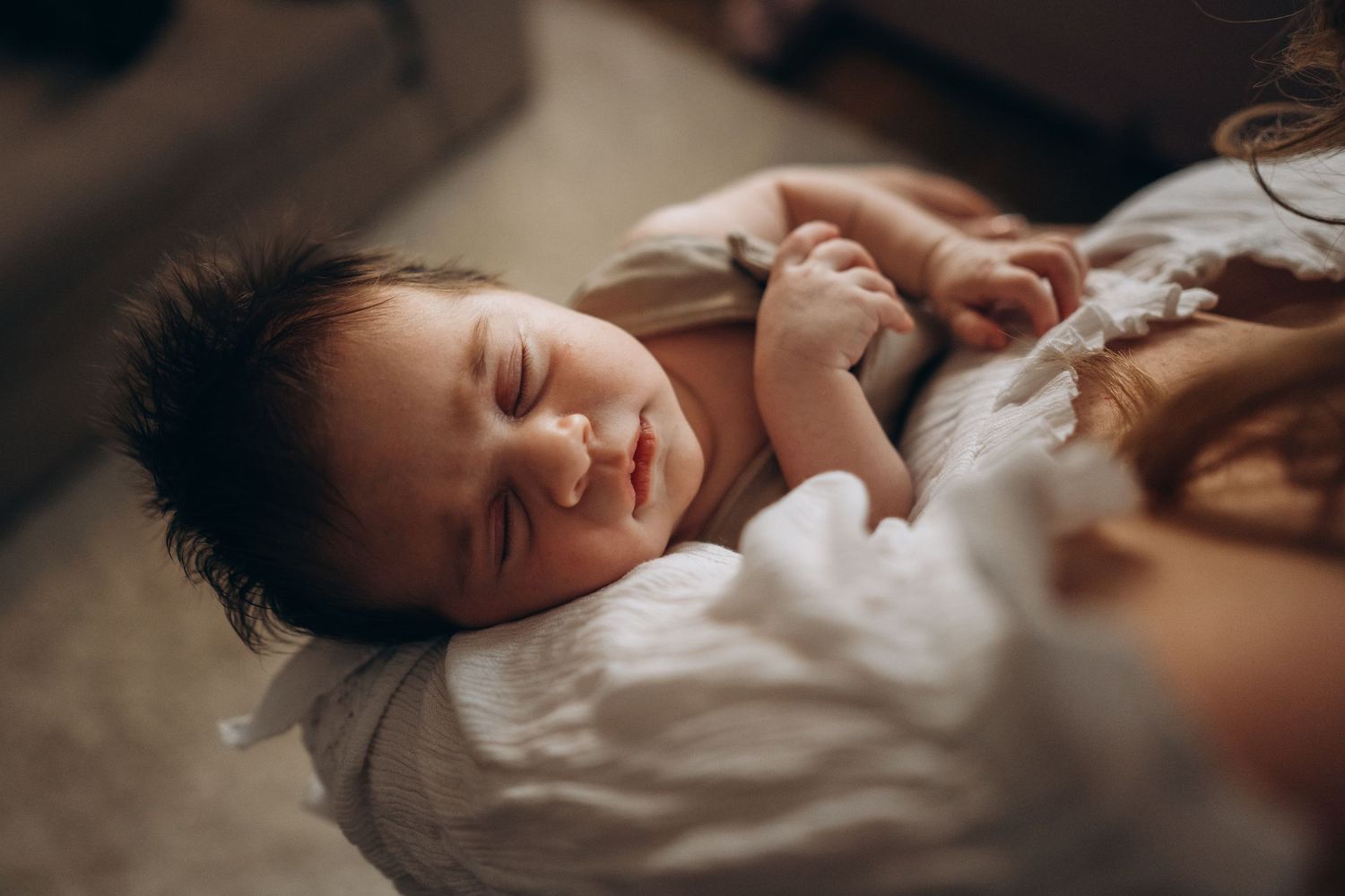 a new born baby sleeping in her mother's arms, kent new born photographer