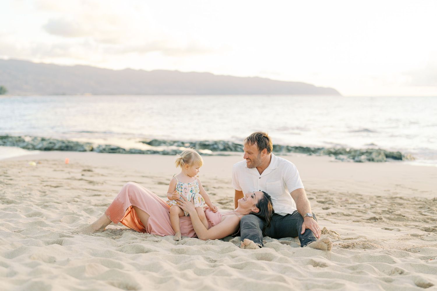 Joyful family moment captured on a rocky beach at sunset.