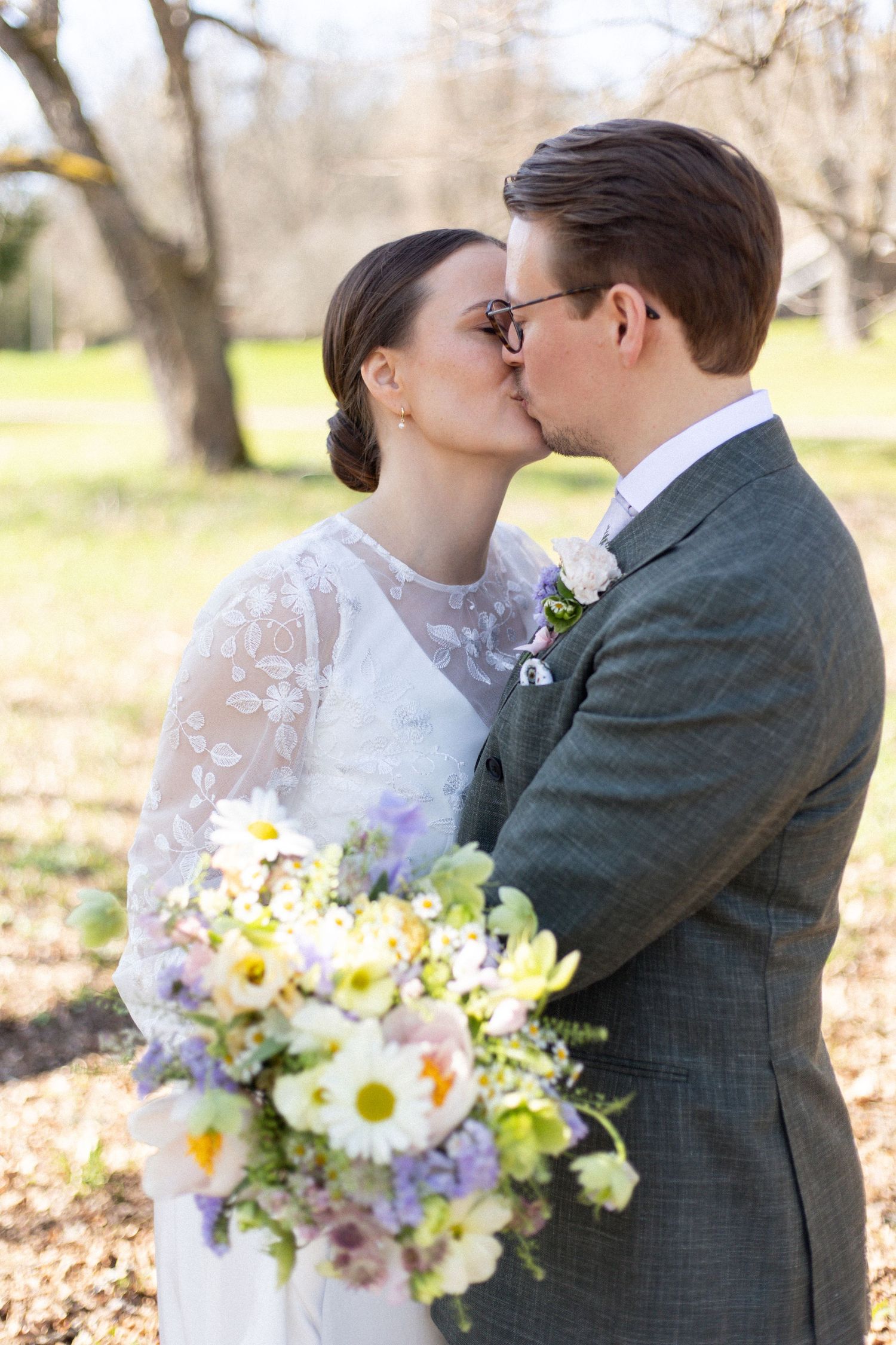 Spring wedding portrait outdoors with yellow daisies and purple wildflowers in the bouquet.