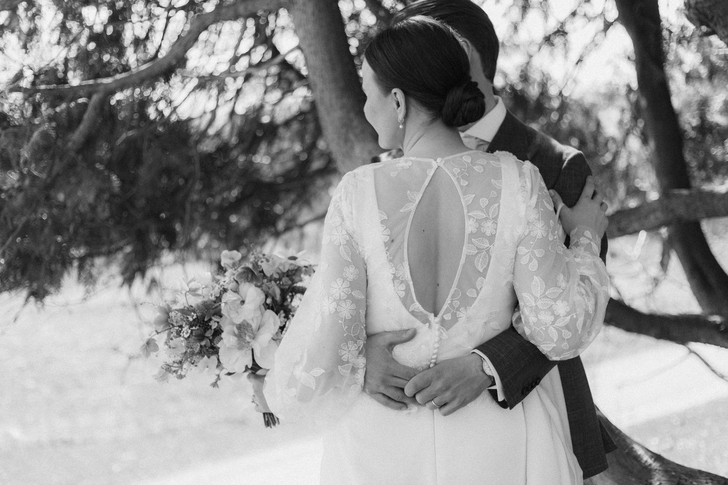 Black and white photo showing the back detail of a lace wedding dress.