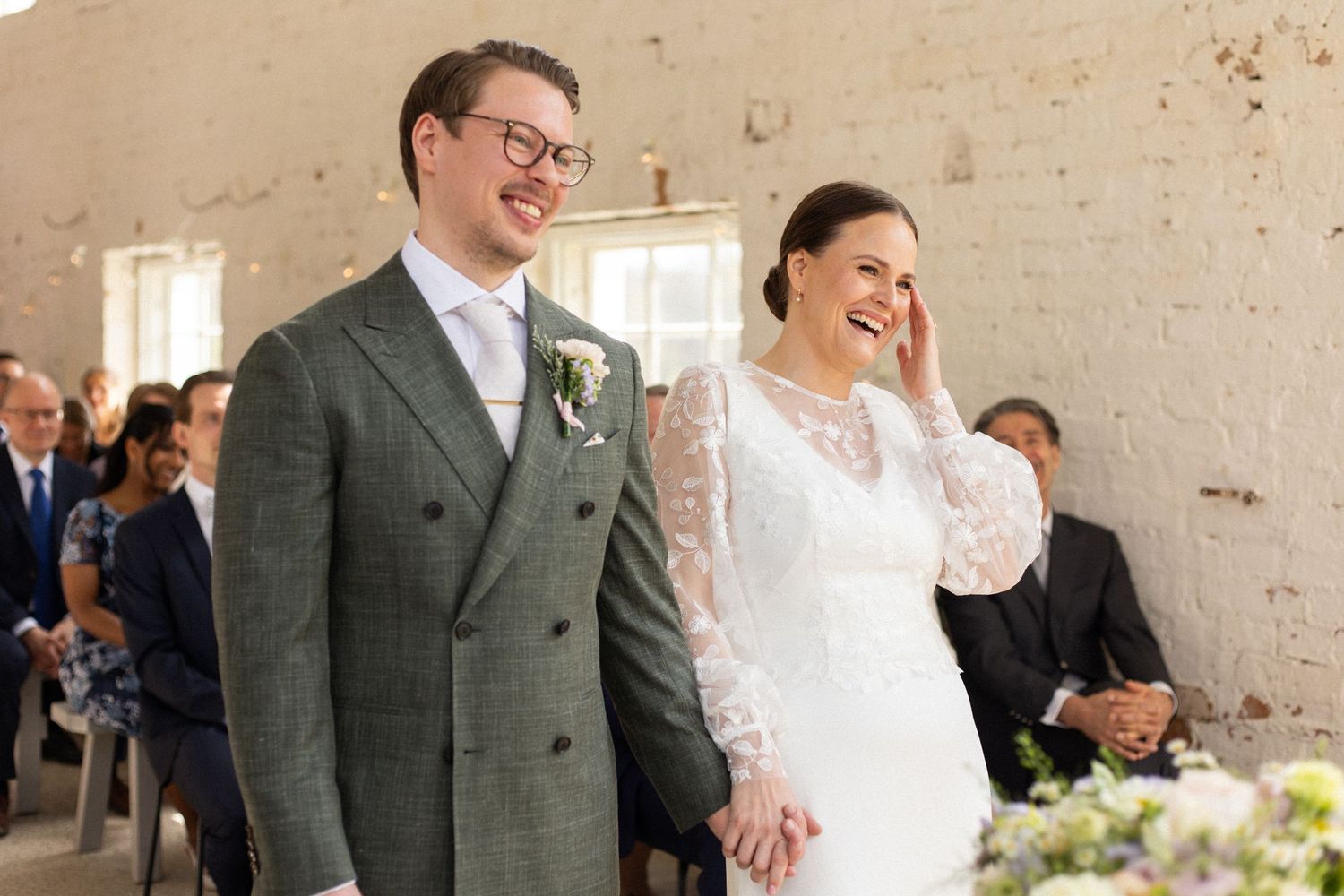 A candid moment of laughter during a bright indoor wedding ceremony.