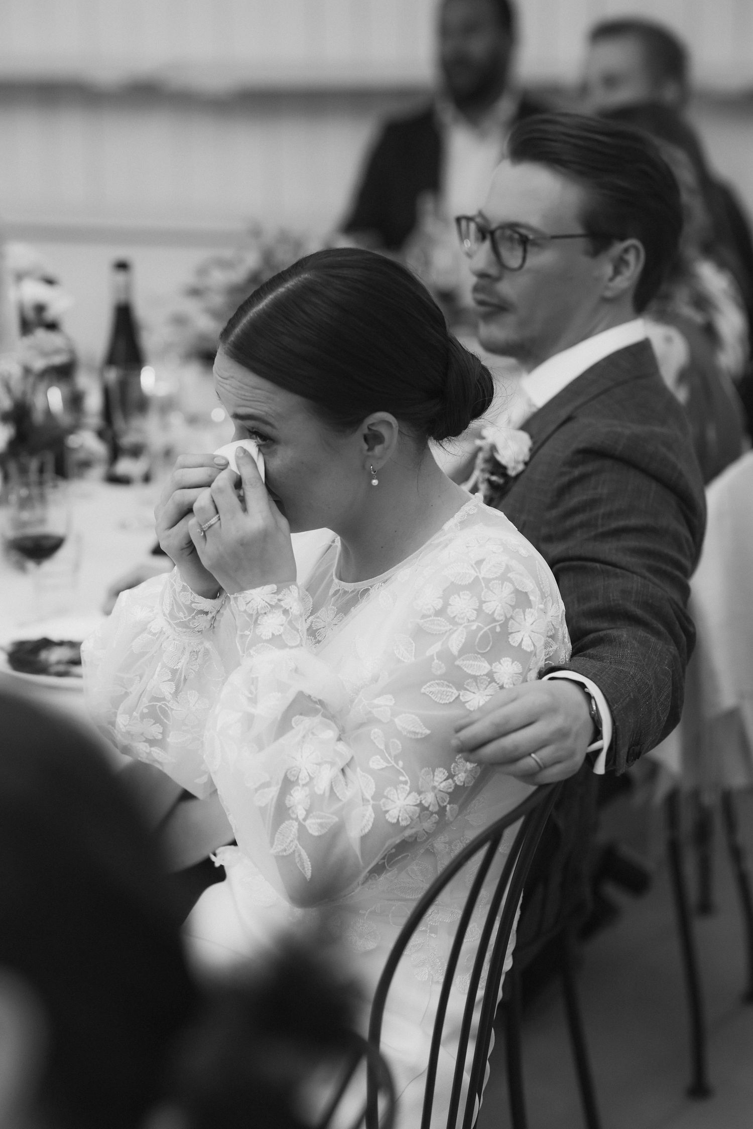 An emotional moment captured during wedding speeches at an indoor reception.