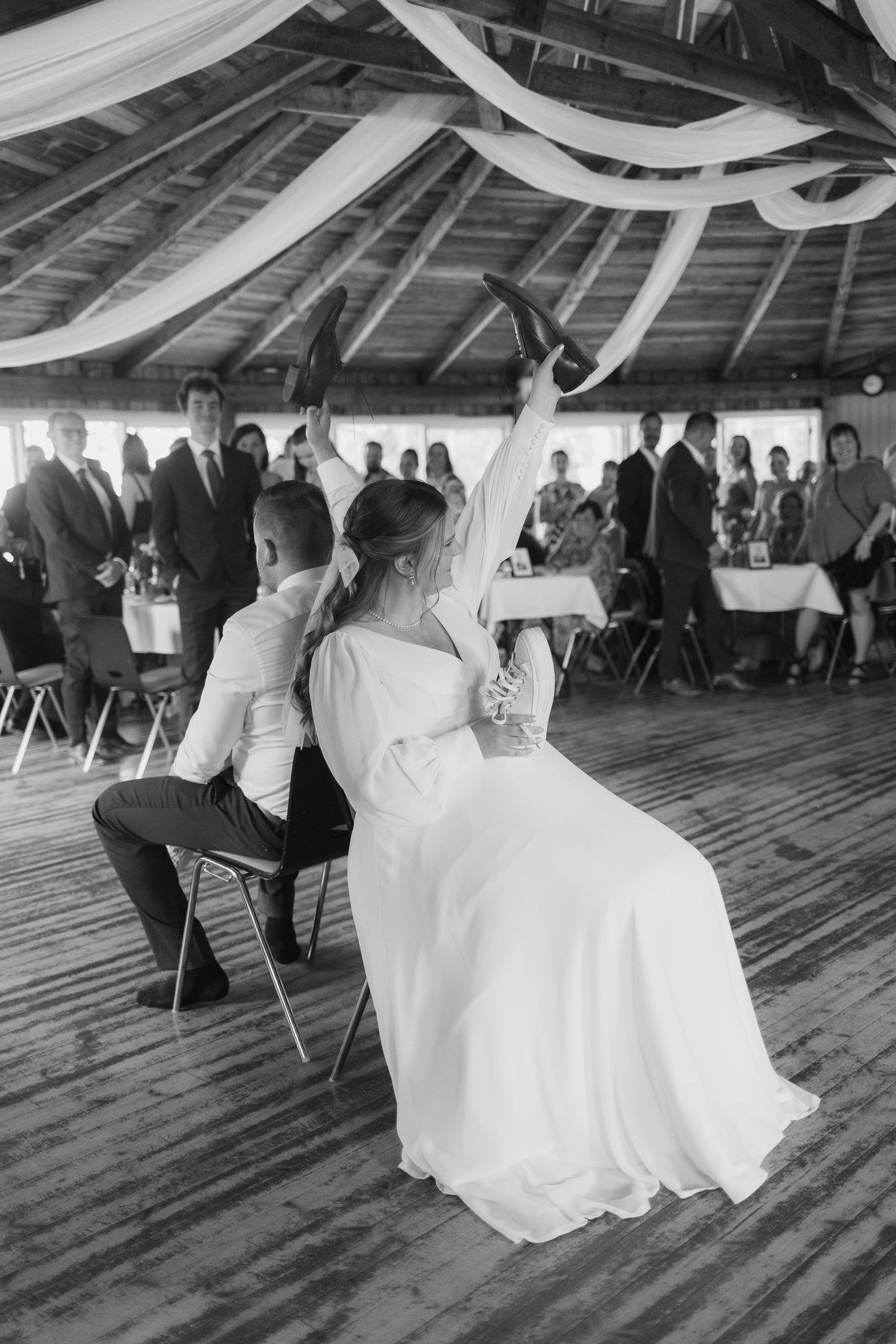 Wedding celebration in rustic venue with white fabric draped from ceiling beams.