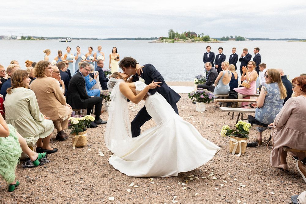 A series of candid wedding photos showing guests gathered on a beach with a dog and bride's dress flowing in the breeze.