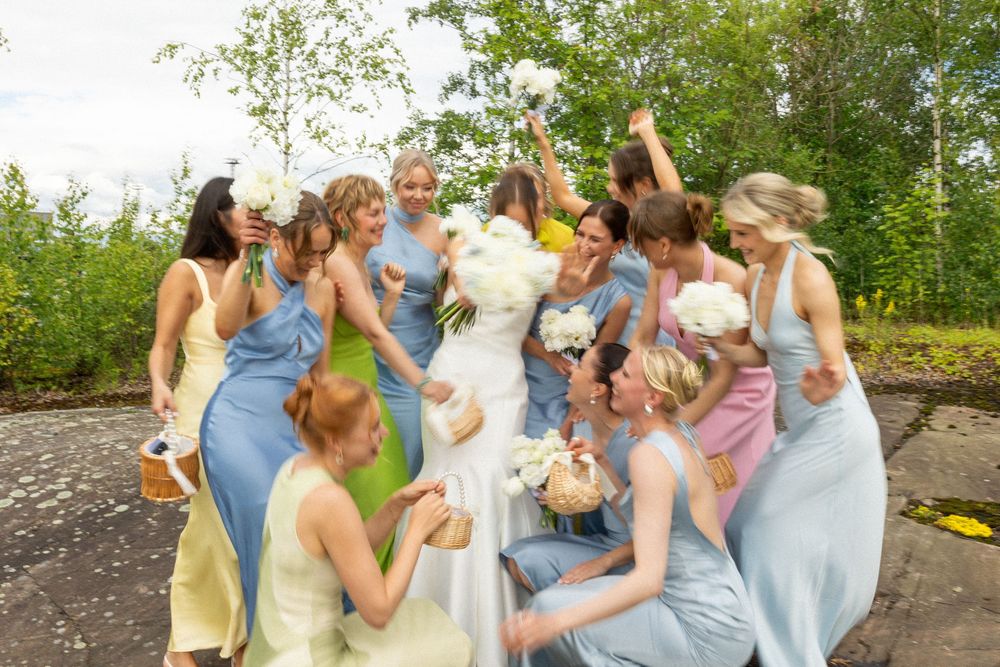 Group of wedding guests participate in an outdoor game forming a human chain in a garden setting.