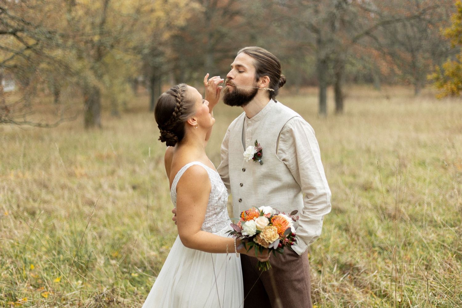 A couple sharing an intimate moment in a rustic autumn field with orange flowers.