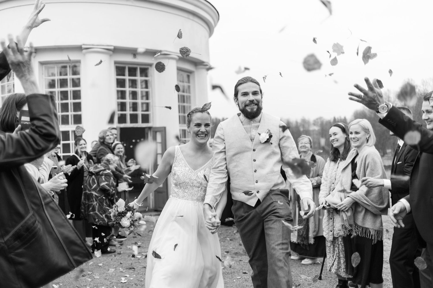 A joyful wedding celebration with confetti being thrown outside a white building.