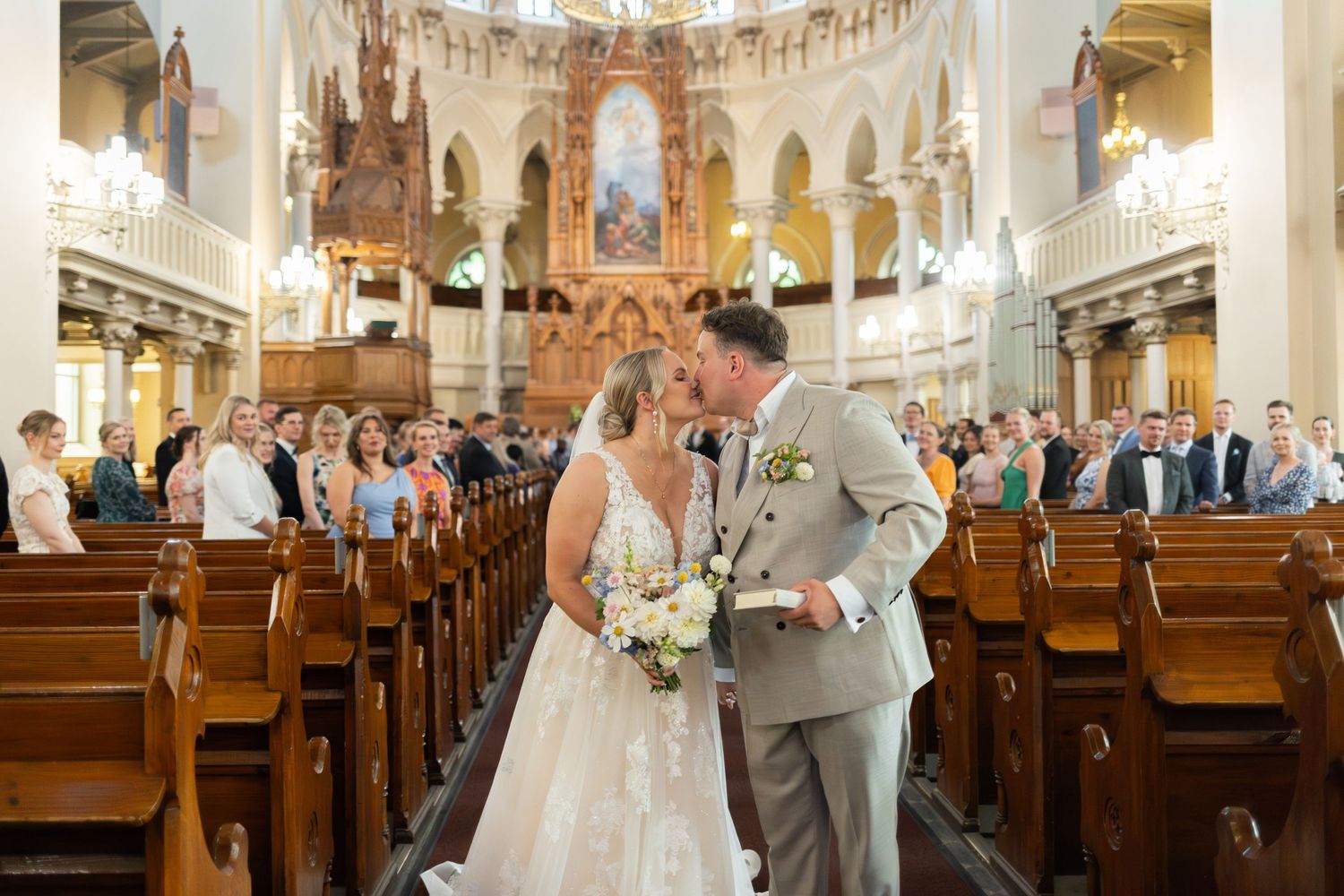 A wedding ceremony taking place inside an ornate church with elegant architecture.