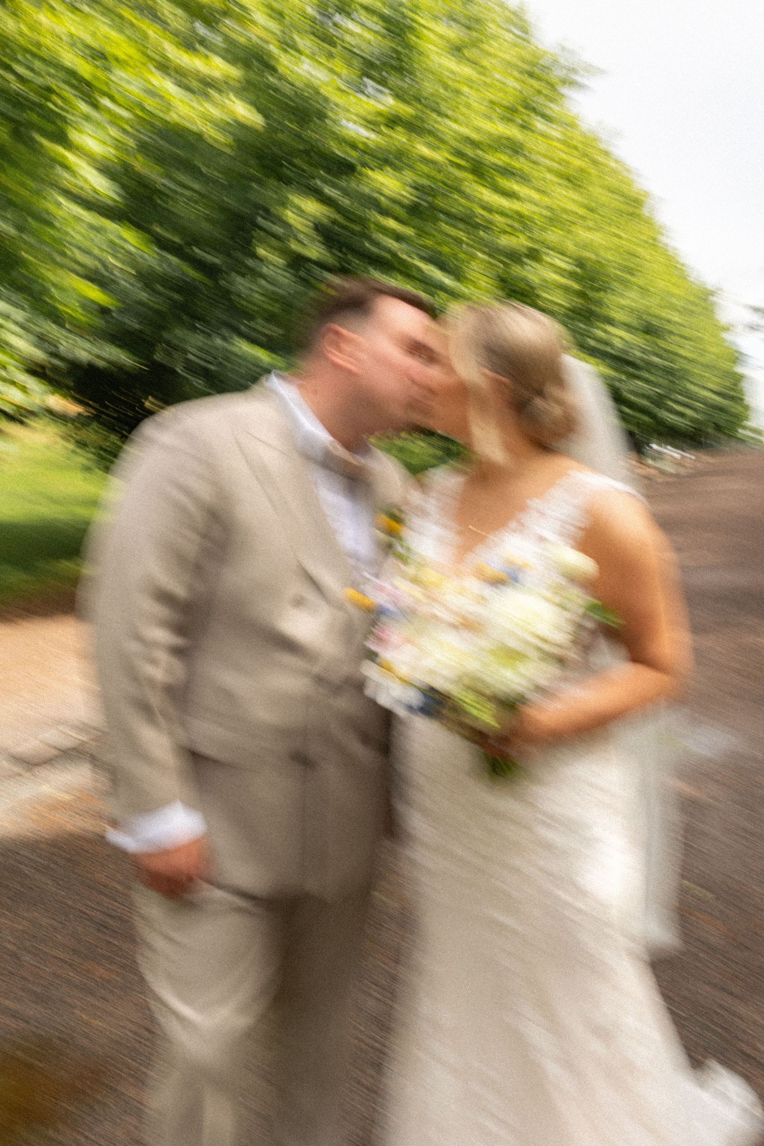 Motion-blur wedding photo with green foliage background.