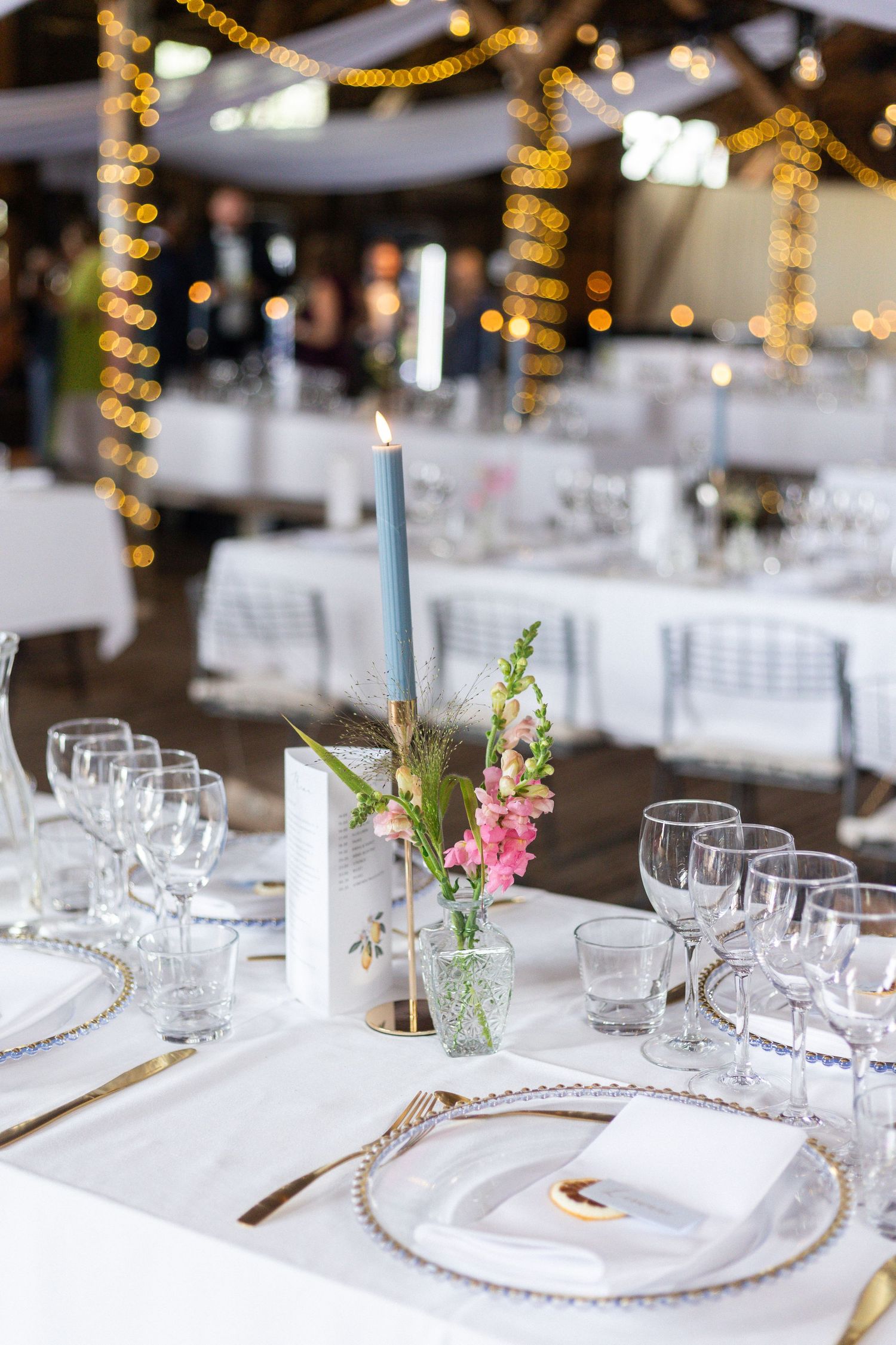 Elegant wedding reception table with twinkling lights and delicate floral centerpiece.