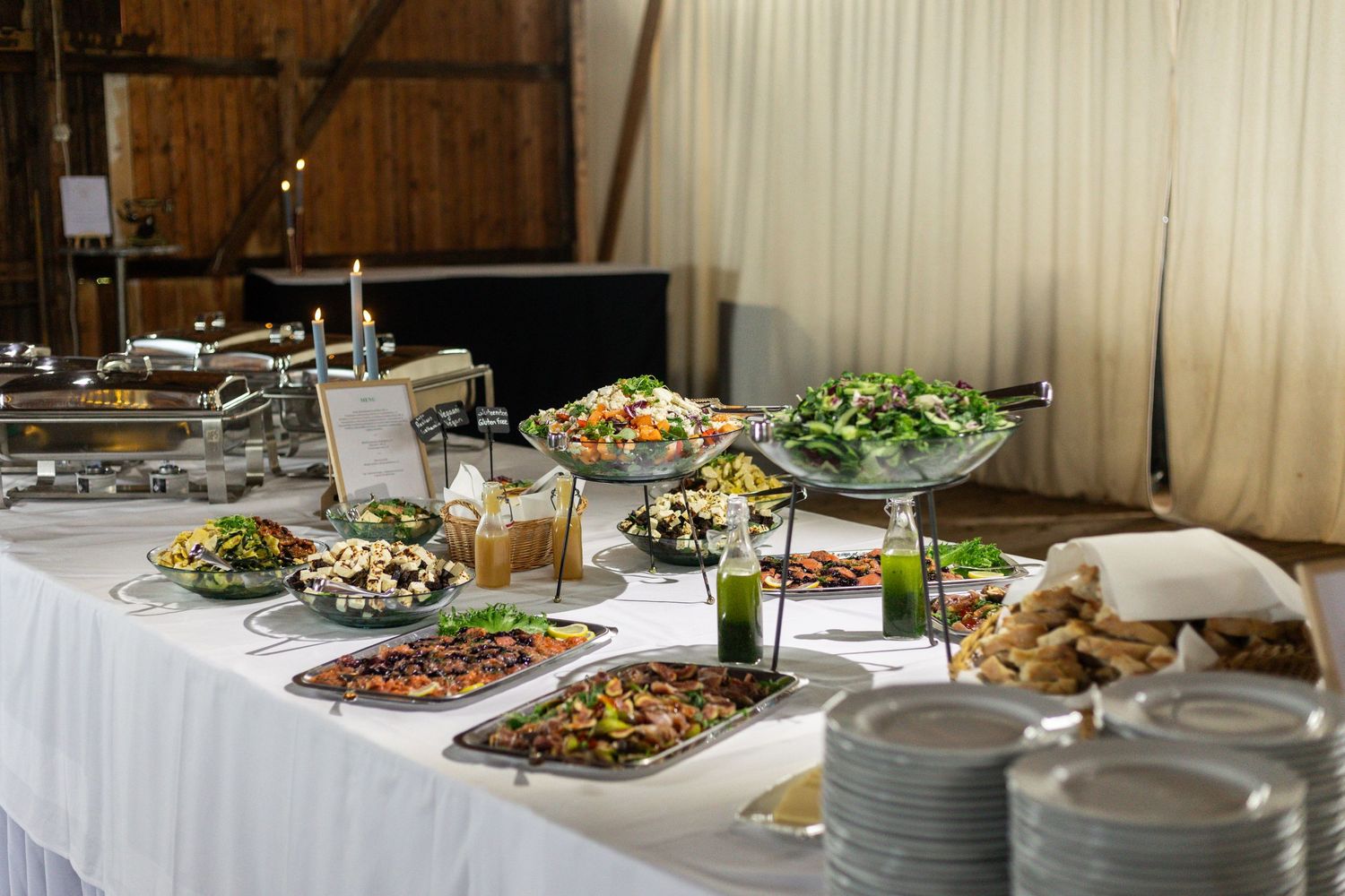 An elegant buffet table set with various dishes and salads on white tablecloths for a catered event.