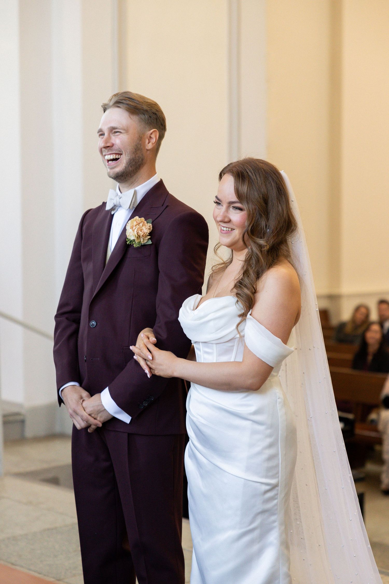 A couple shares a joyful moment during their wedding ceremony in a church.