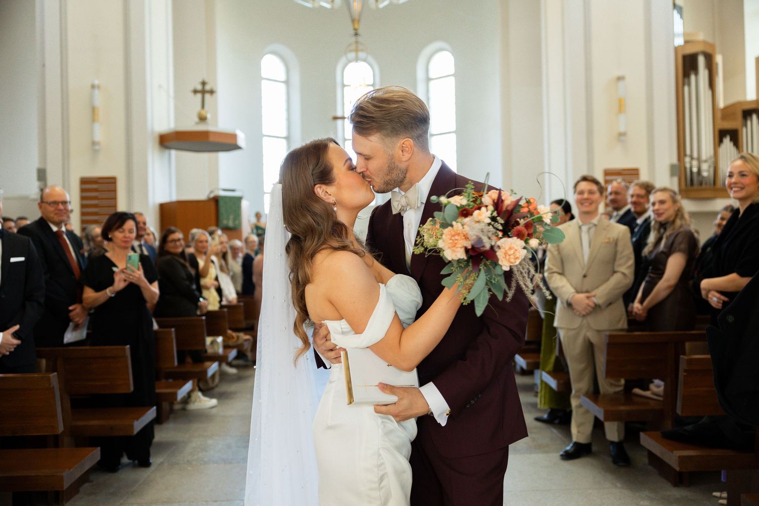 Couple sharing their first kiss as newlyweds in a traditional church setting.