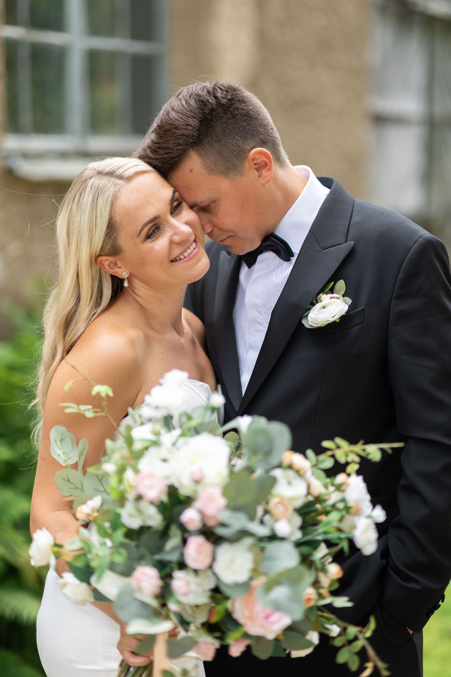 Wedding portrait featuring a romantic moment with a lush floral bouquet.