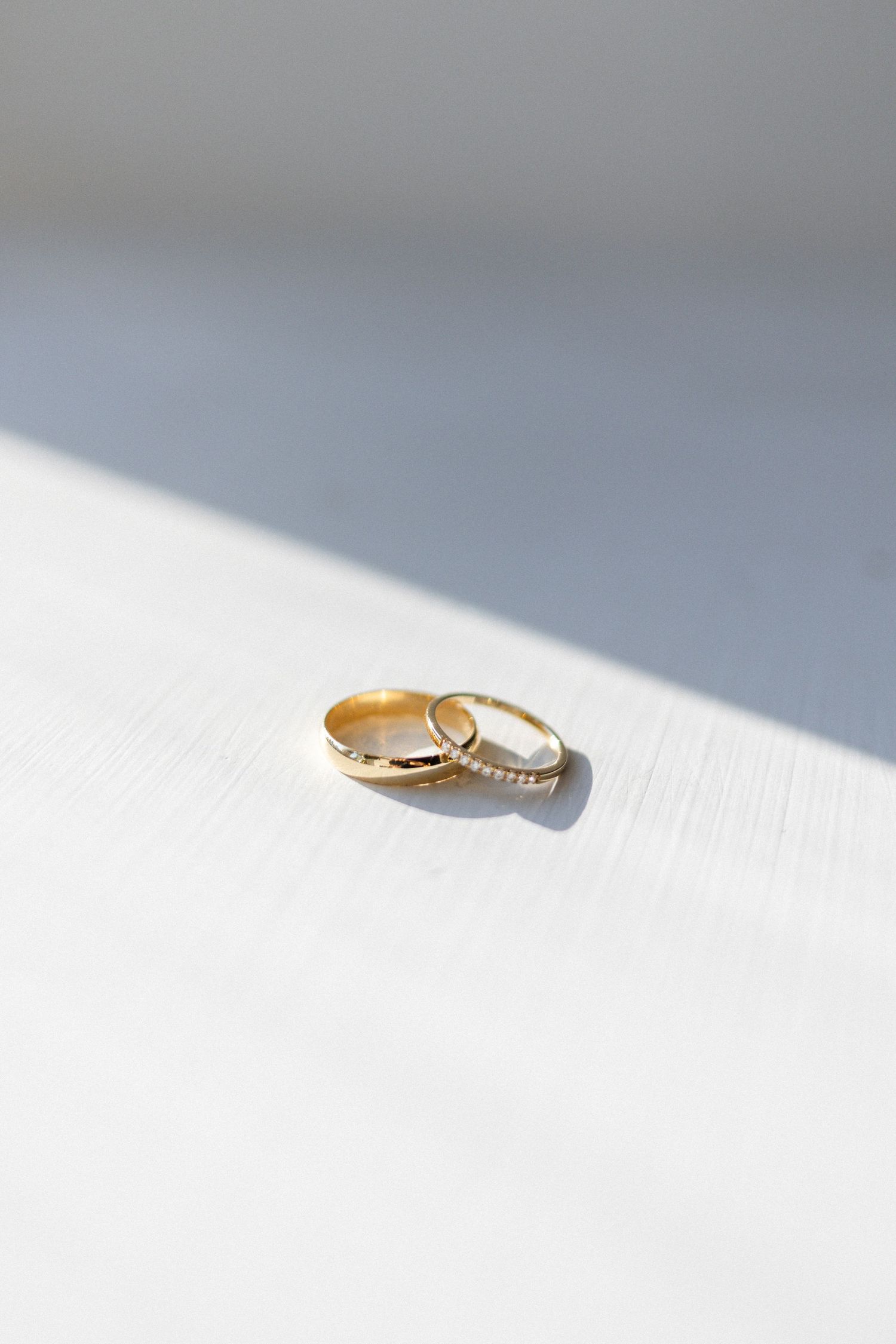 Gold and silver wedding rings photographed with dramatic lighting and shadows.