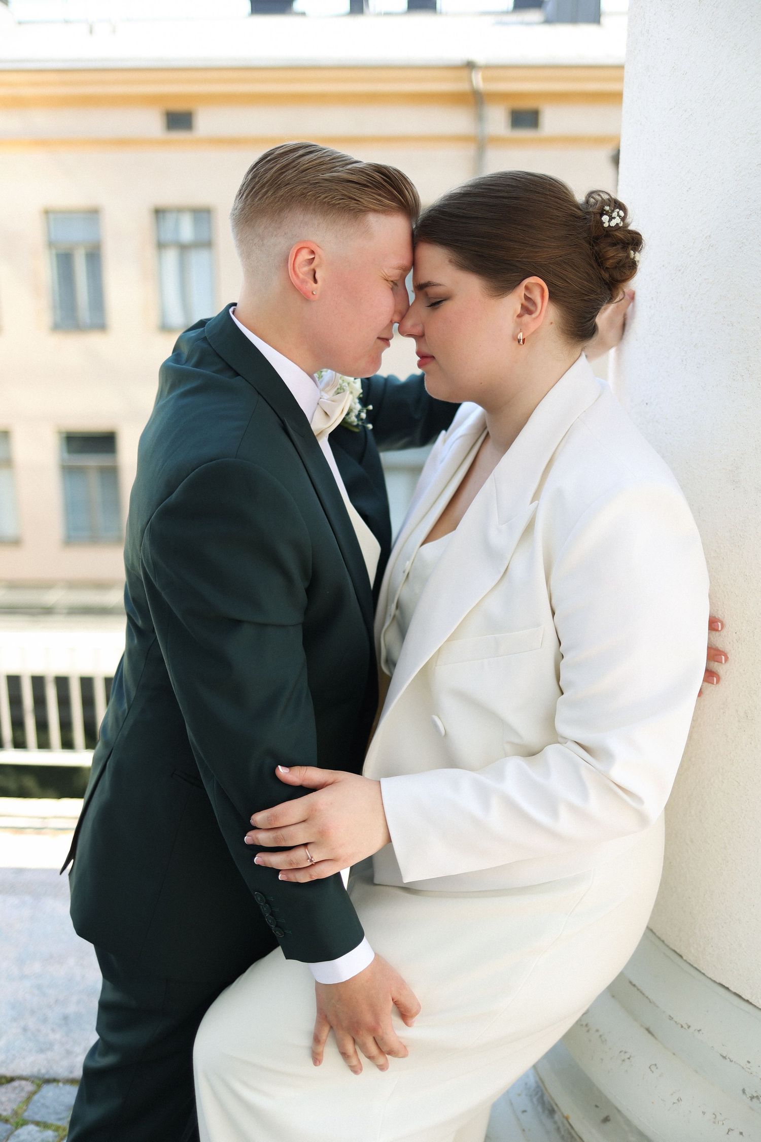 Wedding couple in elegant white and black attire sharing romantic moment outdoors.