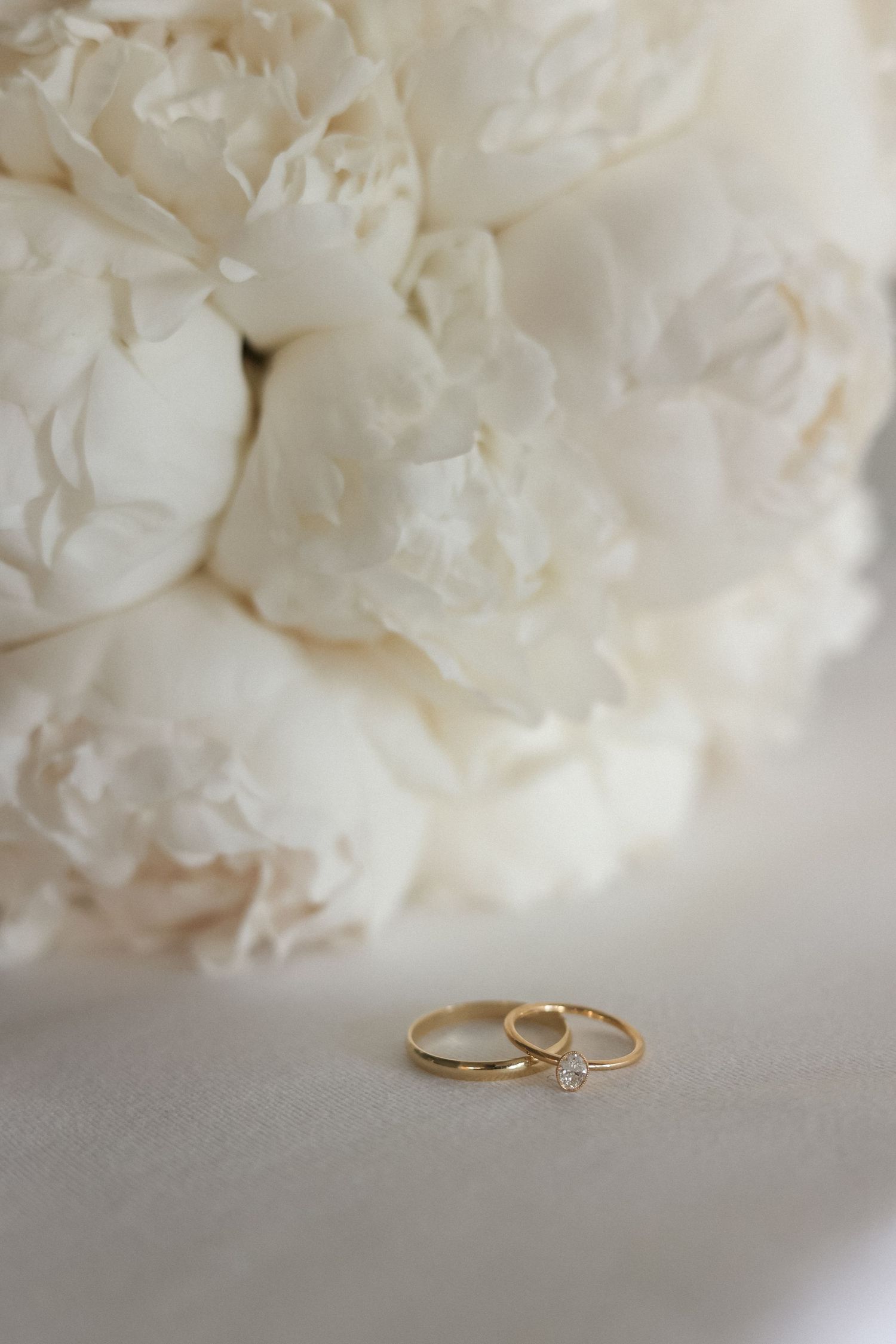 Wedding rings displayed against a backdrop of delicate white peonies.