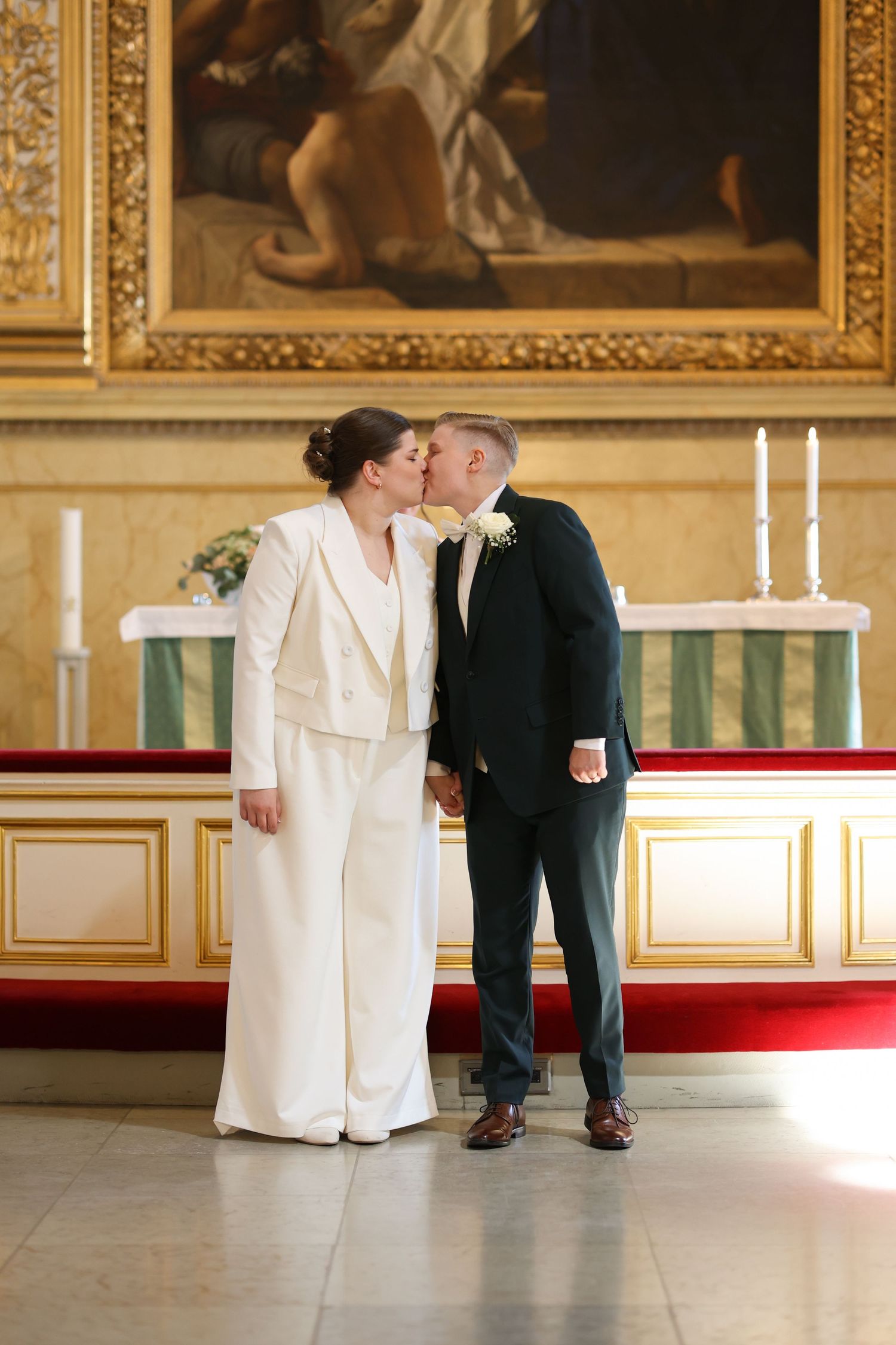 Elegant wedding portrait in ornate room with classical painting and candles.