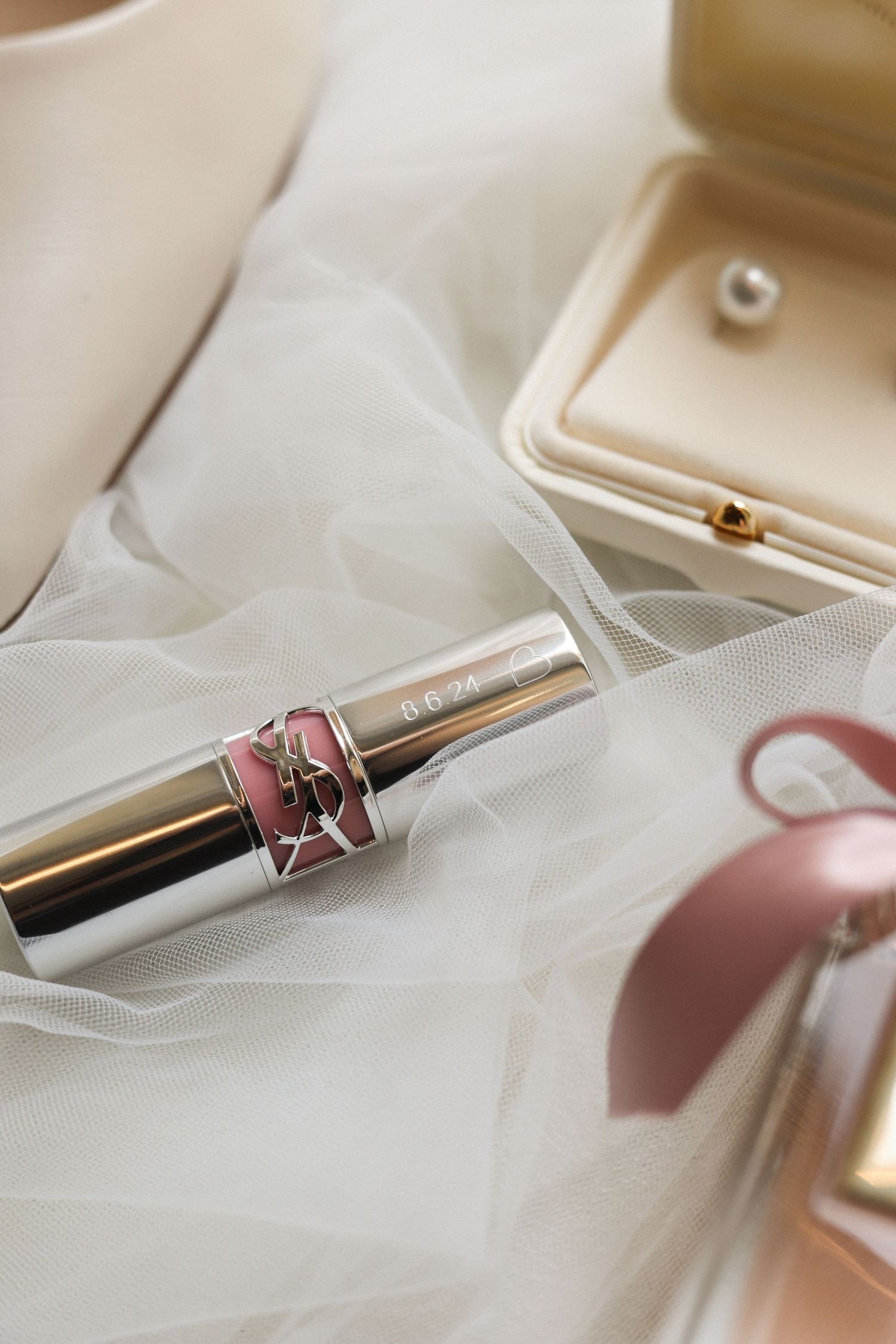 Elegant pink lipstick and tulle veil on a light background with soft styling.