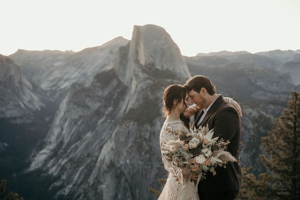 Wedding couple embracing against the backdrop of Yosemite's iconic Half Dome.