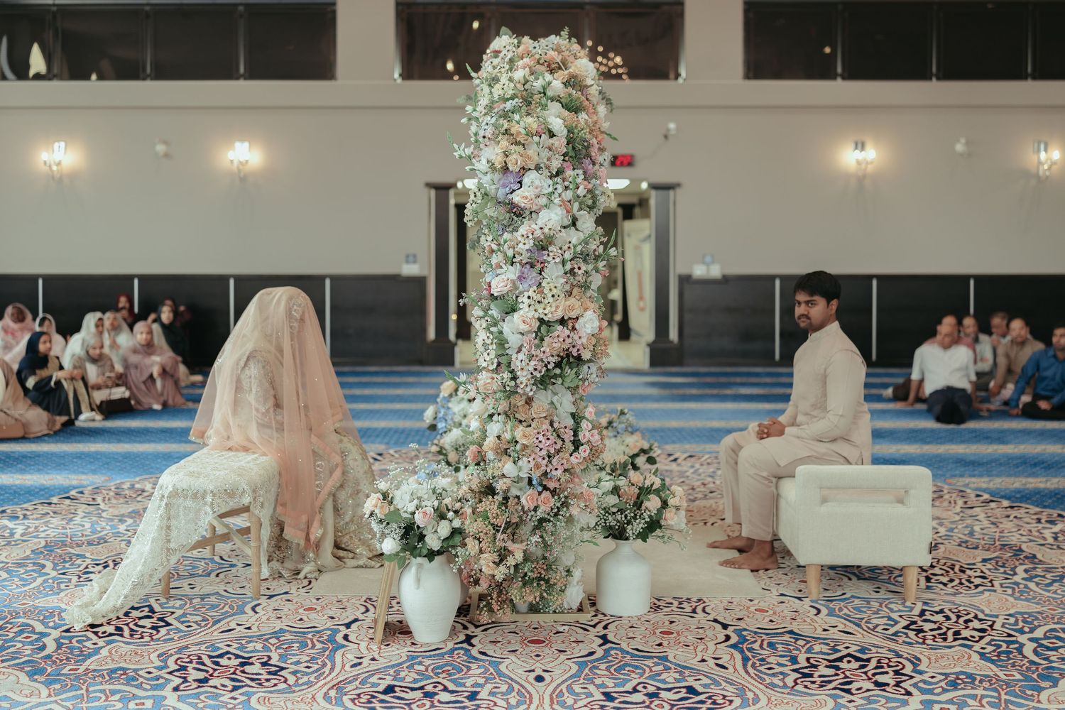 Elegant wedding couple cutting their multi-tiered cake surrounded by red floral decorations.