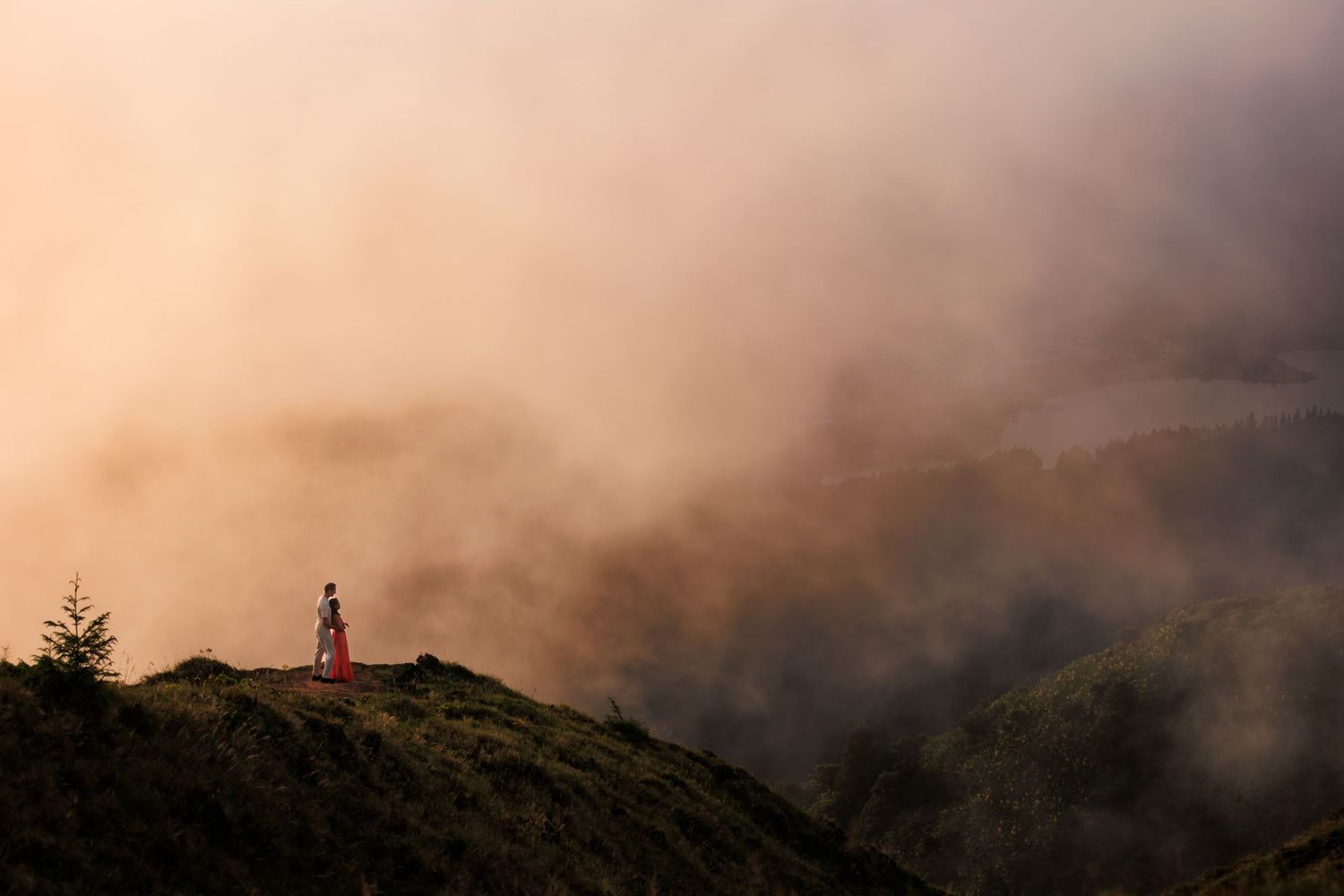 Breathtaking scenery in the clouds, with a view over the crater of Sete Cidades, and a couple embraced enjoying nature.