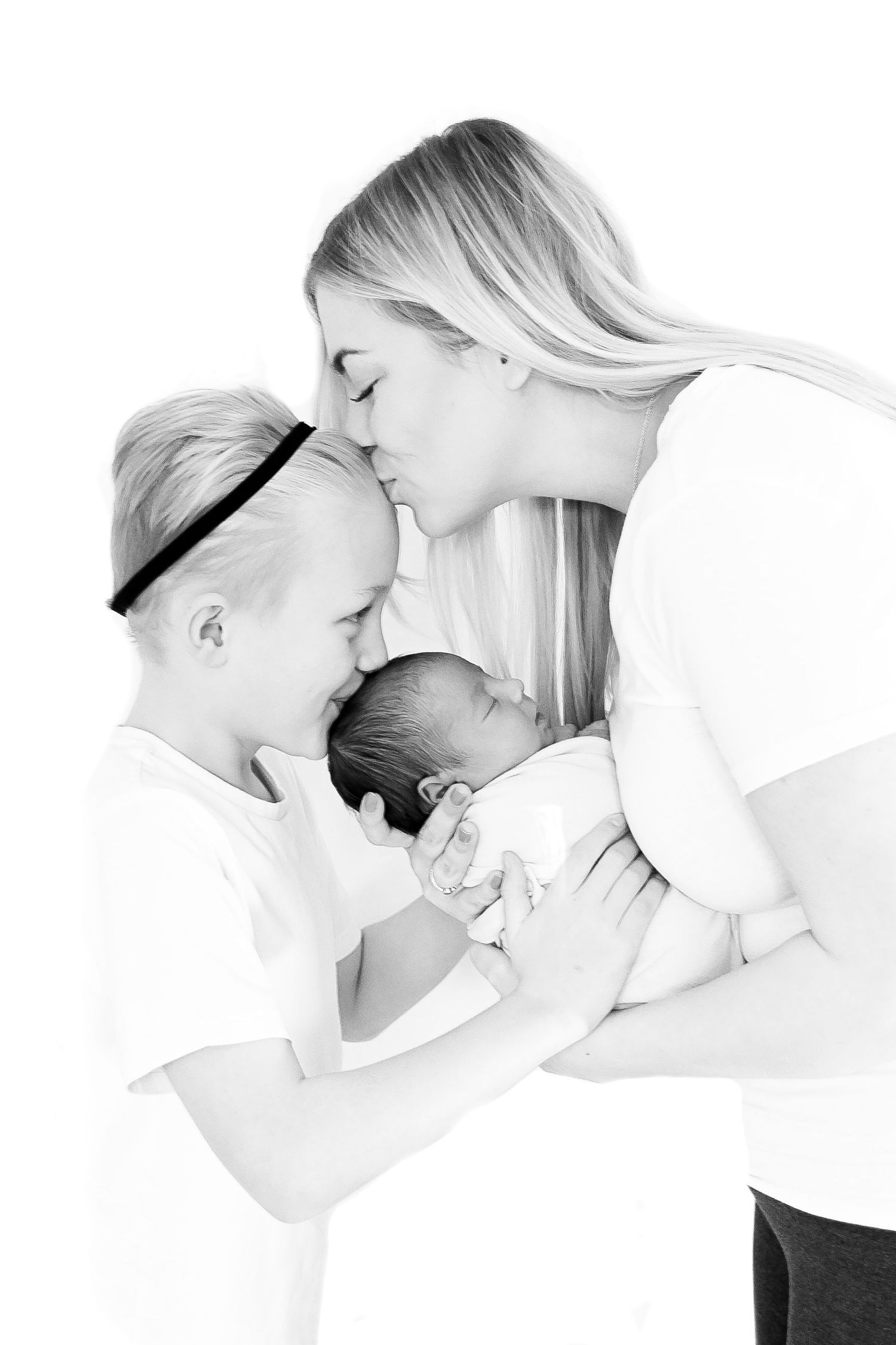 High-key black and white portraits showing tender maternal moments in artistic style.