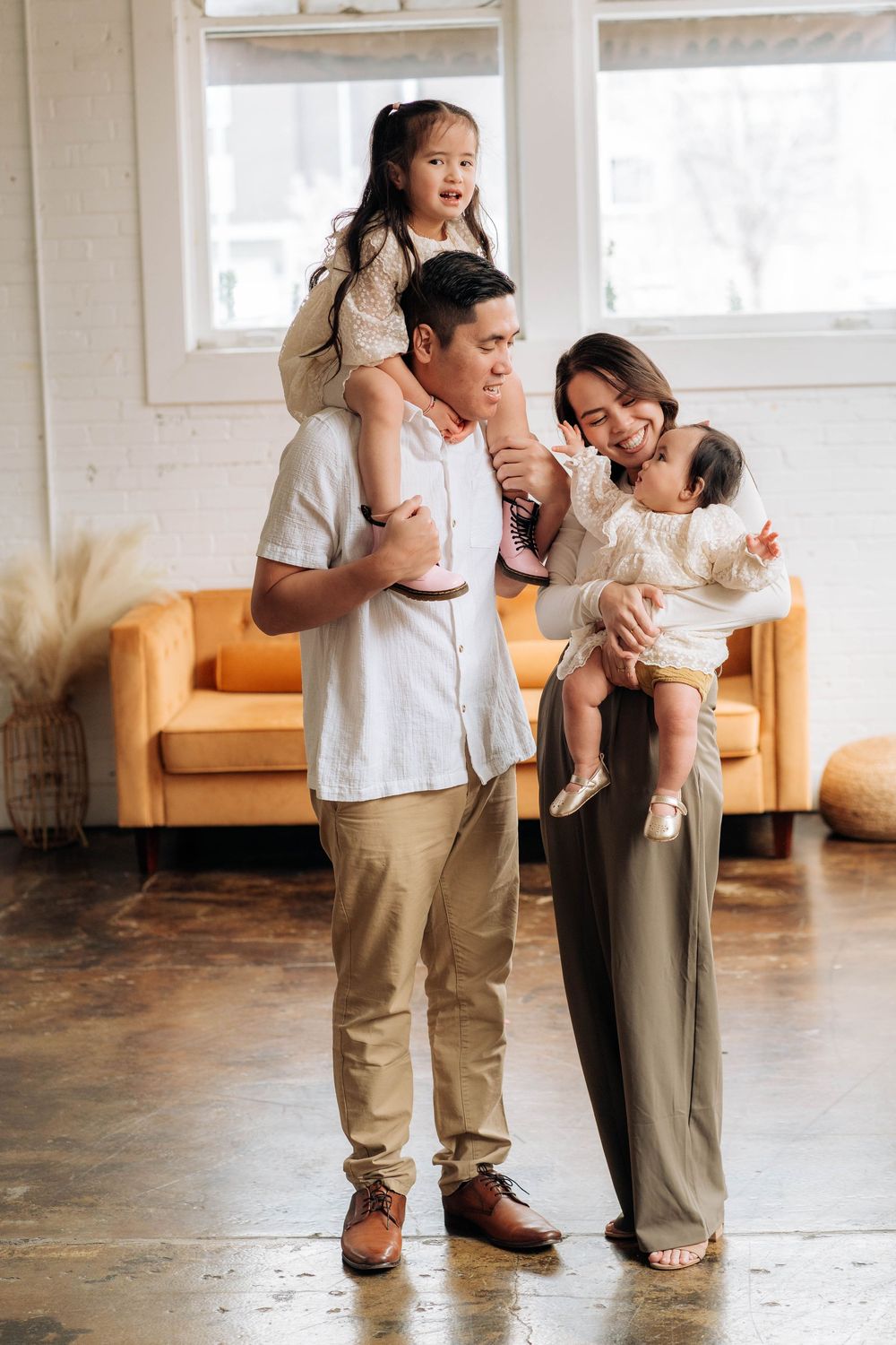 A family enjoying quality time together in a bright living room with hardwood floors and an orange sofa.