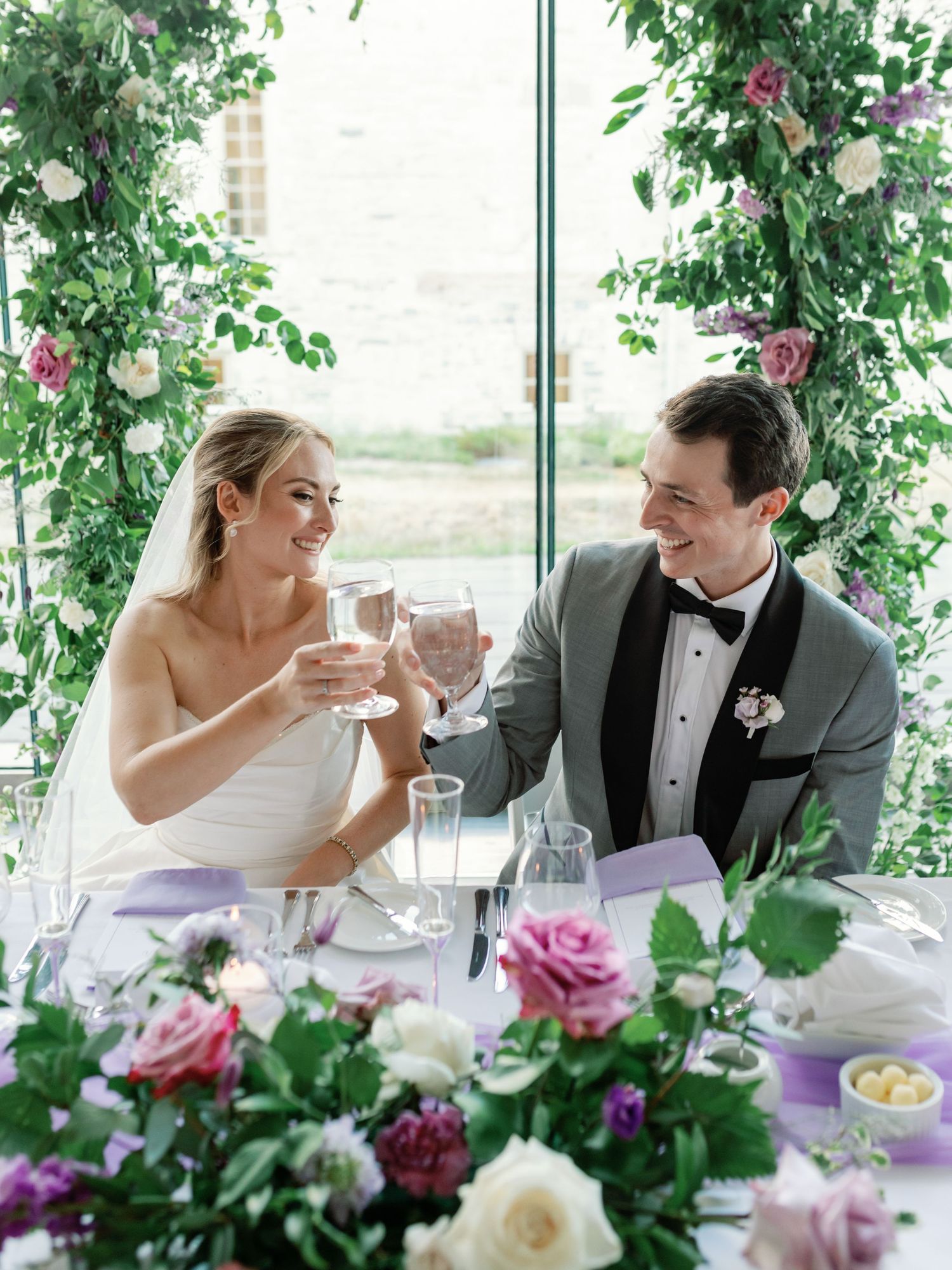 A bride and groom raise their glasses to each other in cheers at the Isabel Bader Centre. Taken by: Katie Crane