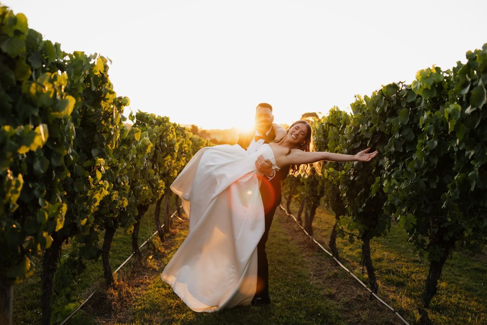 Couple sharing romantic moment in vineyard at sunset with dramatic lighting.