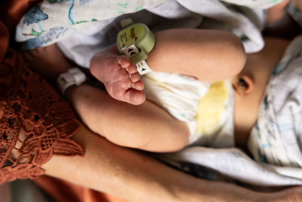 A close-up view of an infant wearing a cloth diaper with a pacifier clip attached.