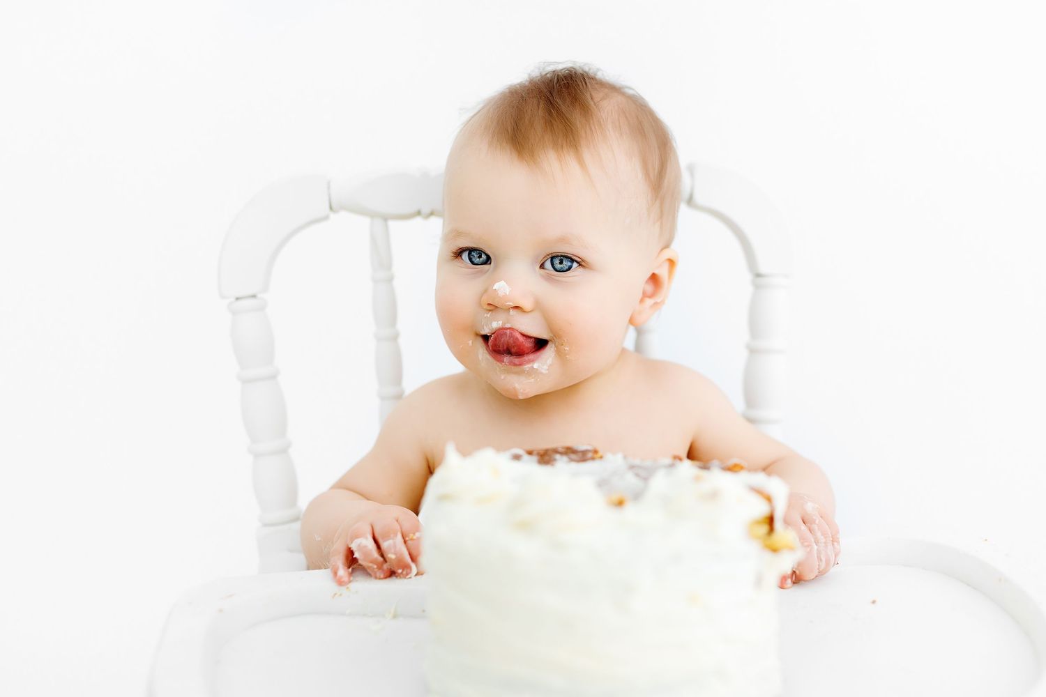 Artistic maternity photo of an expectant mother resting on white bedding in intimate attire.