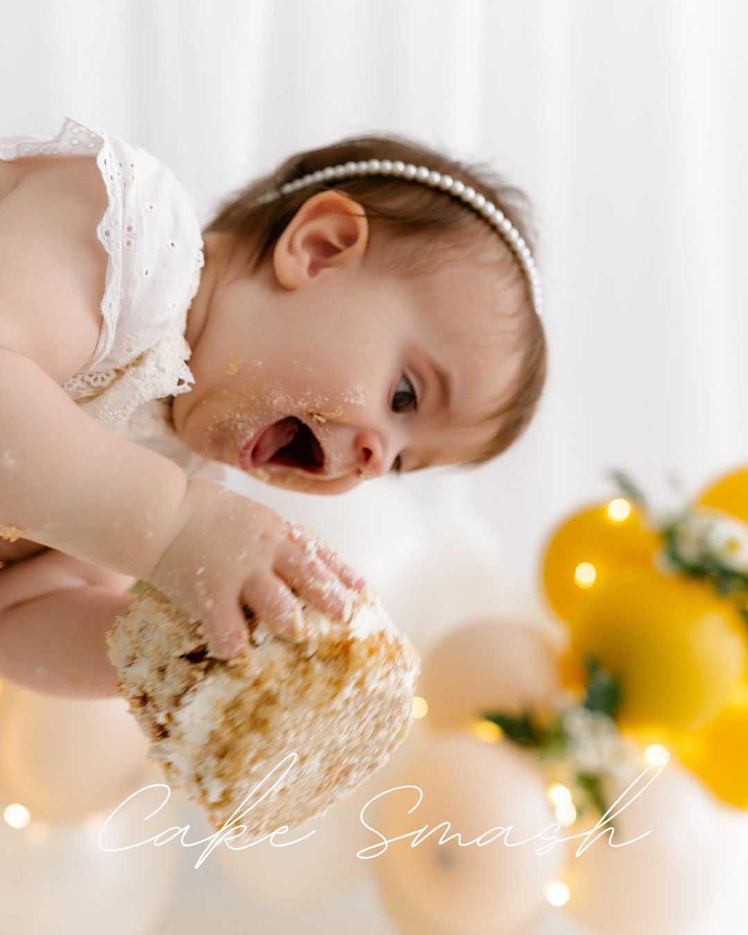 Joyful first birthday celebration photo with white and yellow balloon decorations.