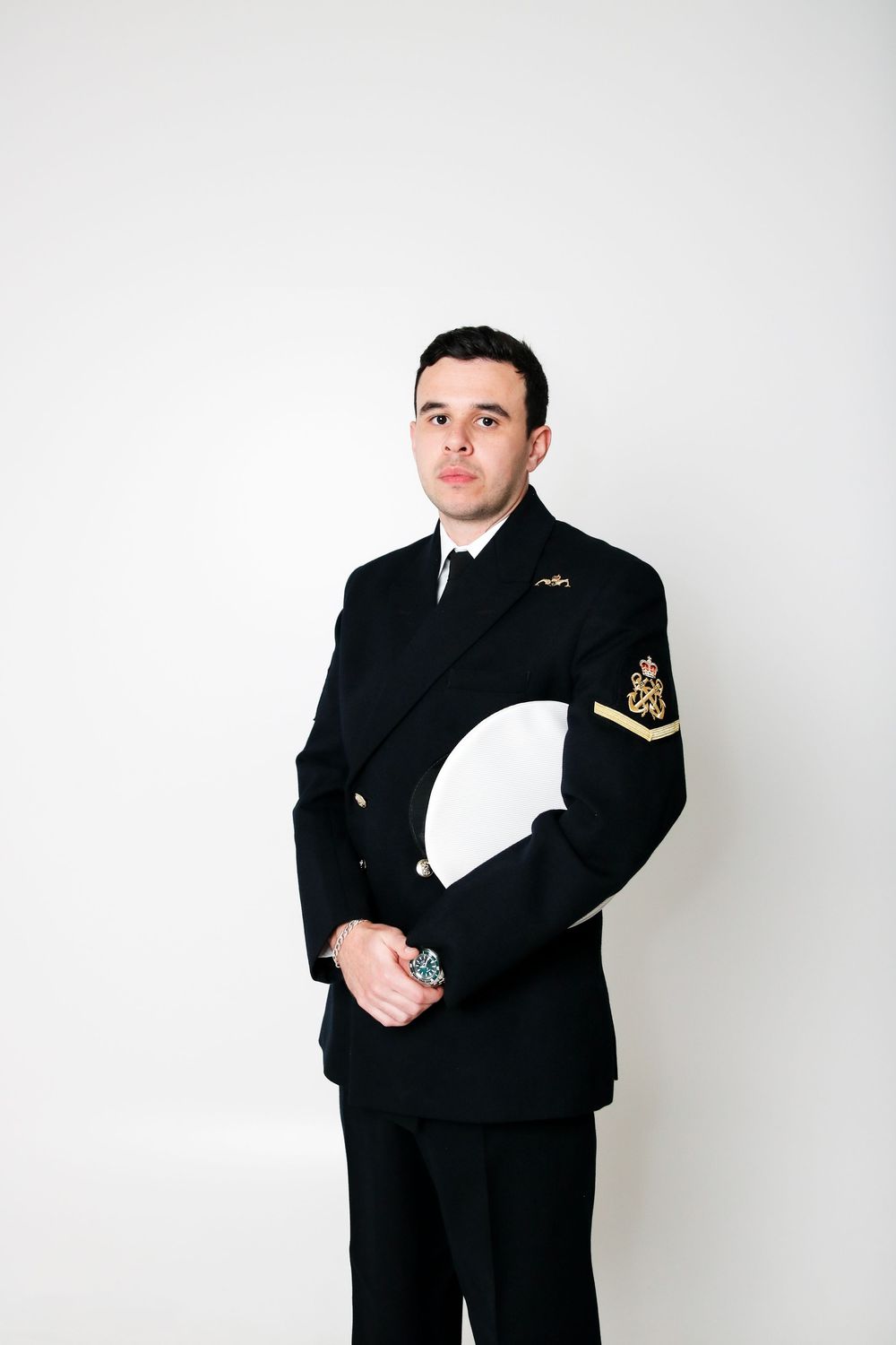 Person in a naval uniform stands at attention against a white background.